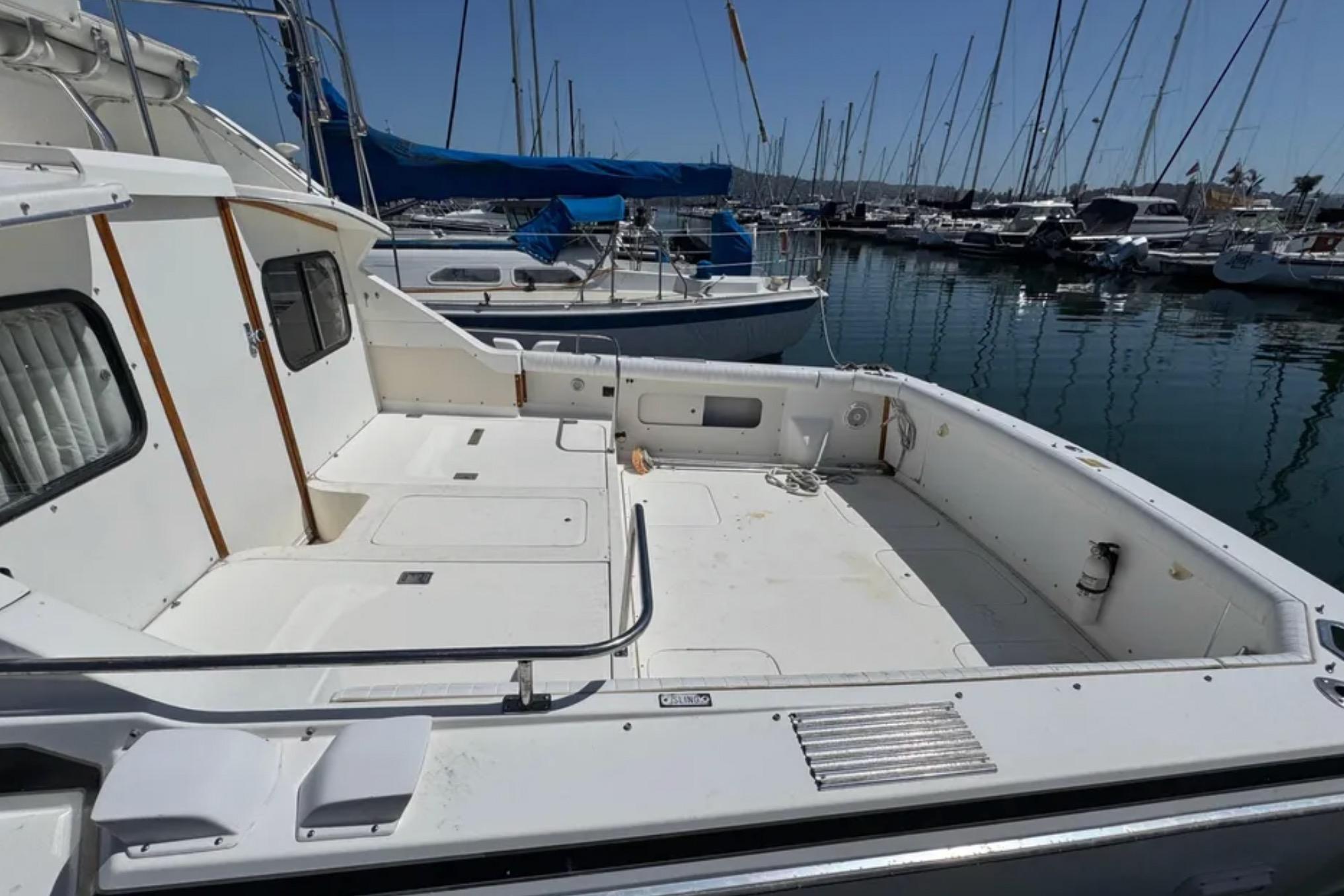 1988 Bertram 28 Sport Fisherman boat docked in marina, spacious deck, clear sky.