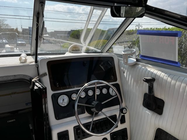 The cockpit of a 1998 Sport-Craft 252 Sport Fish with steering wheel, gauges, and windows.