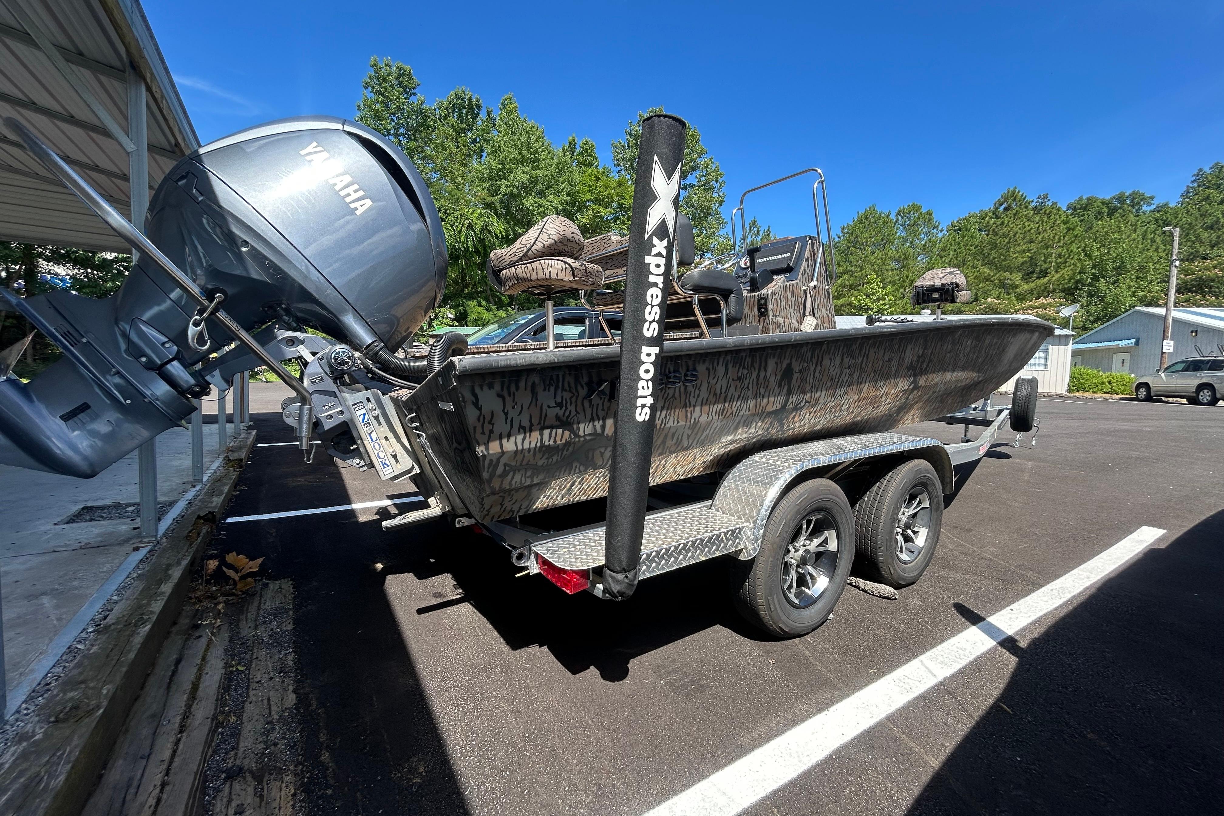 2025 Xpress H22B Bay boat on trailer with Yamaha outboard motor in parking lot.