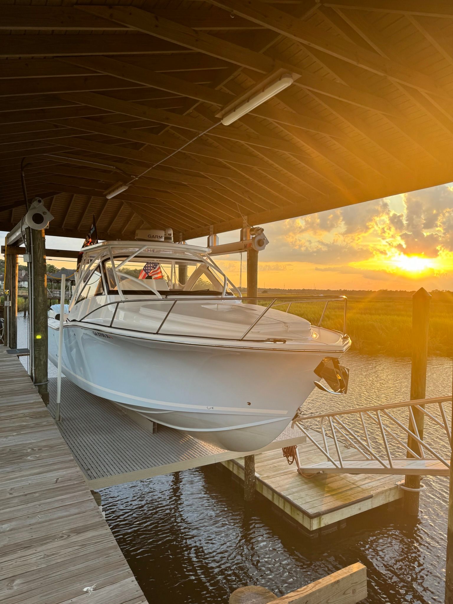 An Albemarle 30 Express boat from 2024 is suspended in a covered dock at sunset.