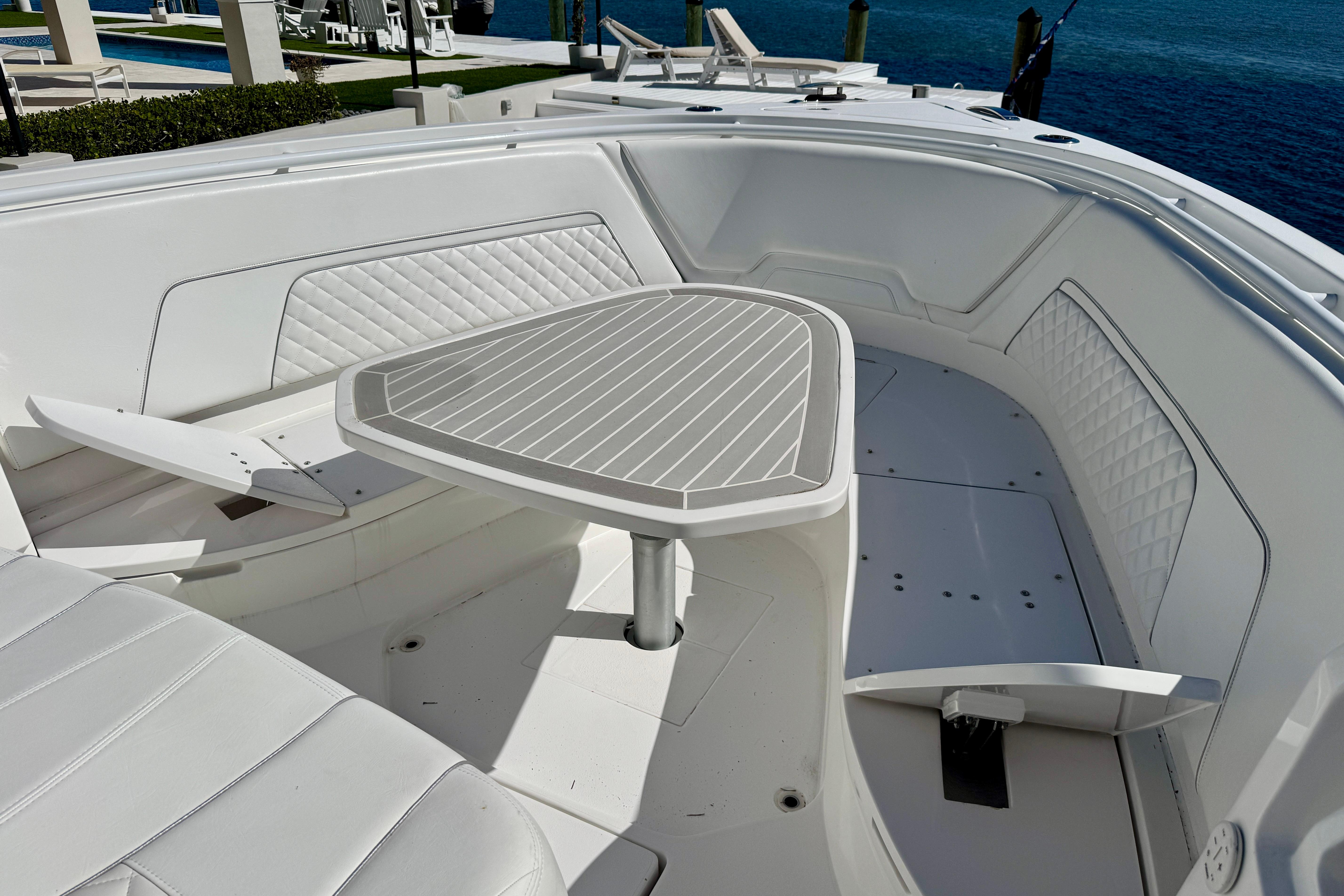 2024 Intrepid 407 Nomad FE boat interior with white seating and table, docked by the water.