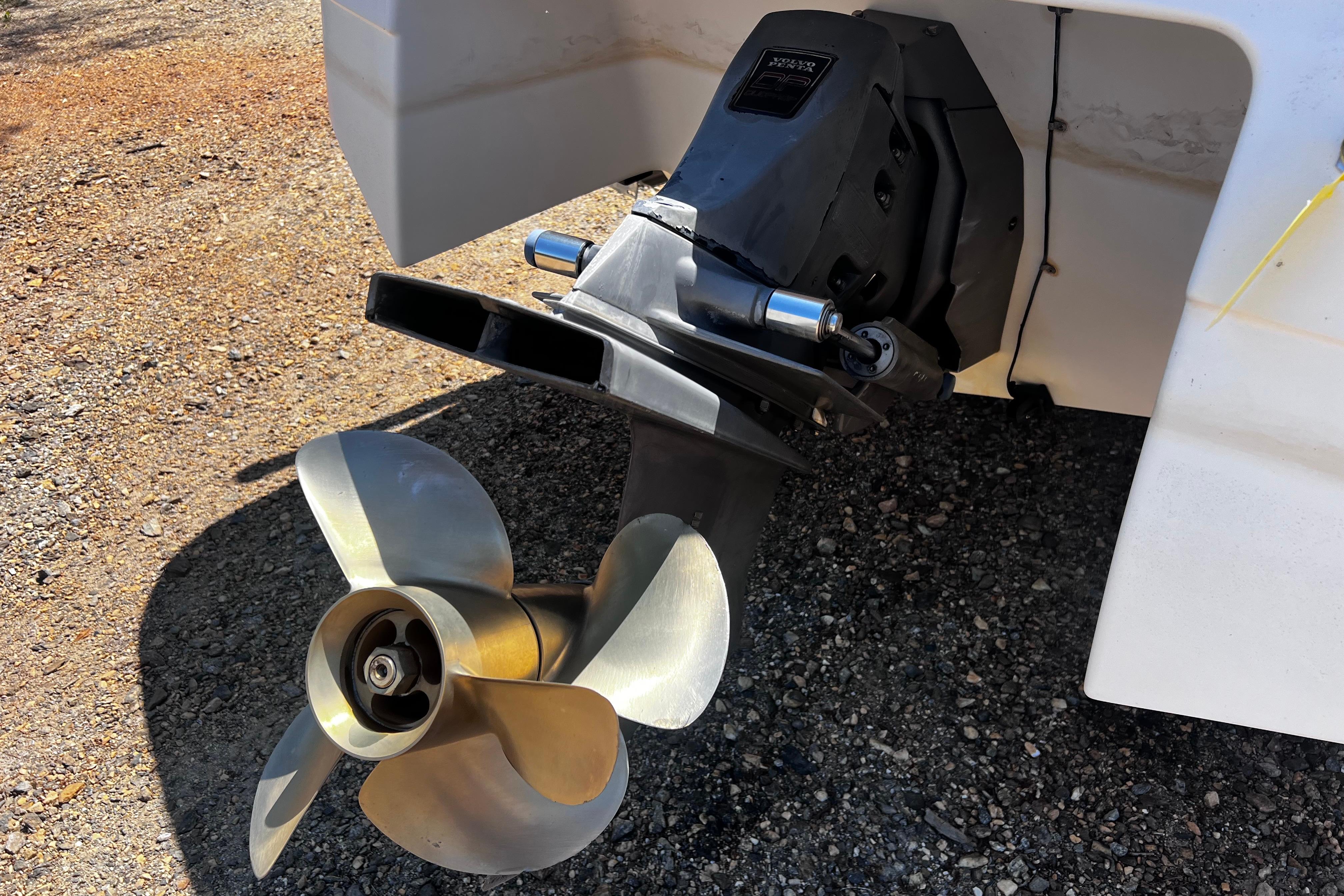 1998 Four Winns 220 Horizon boat propeller and outdrive on gravel surface.