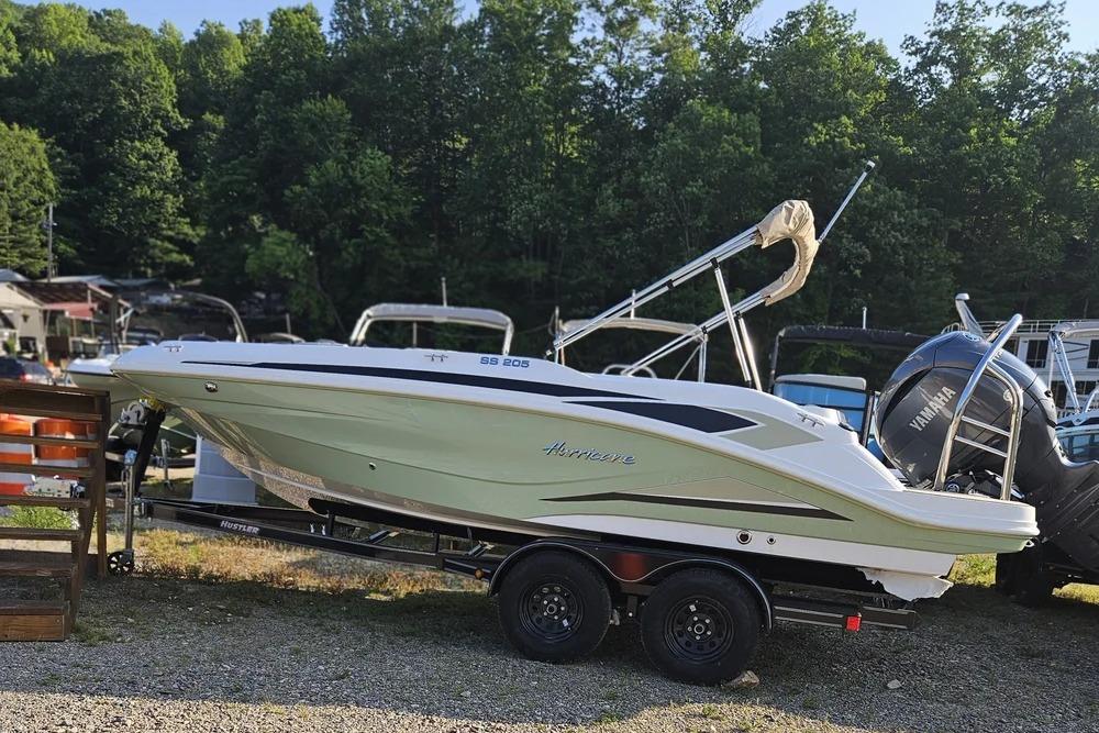 2025 Hurricane SunDeck Sport 205 OB boat on trailer, parked outdoors near trees.