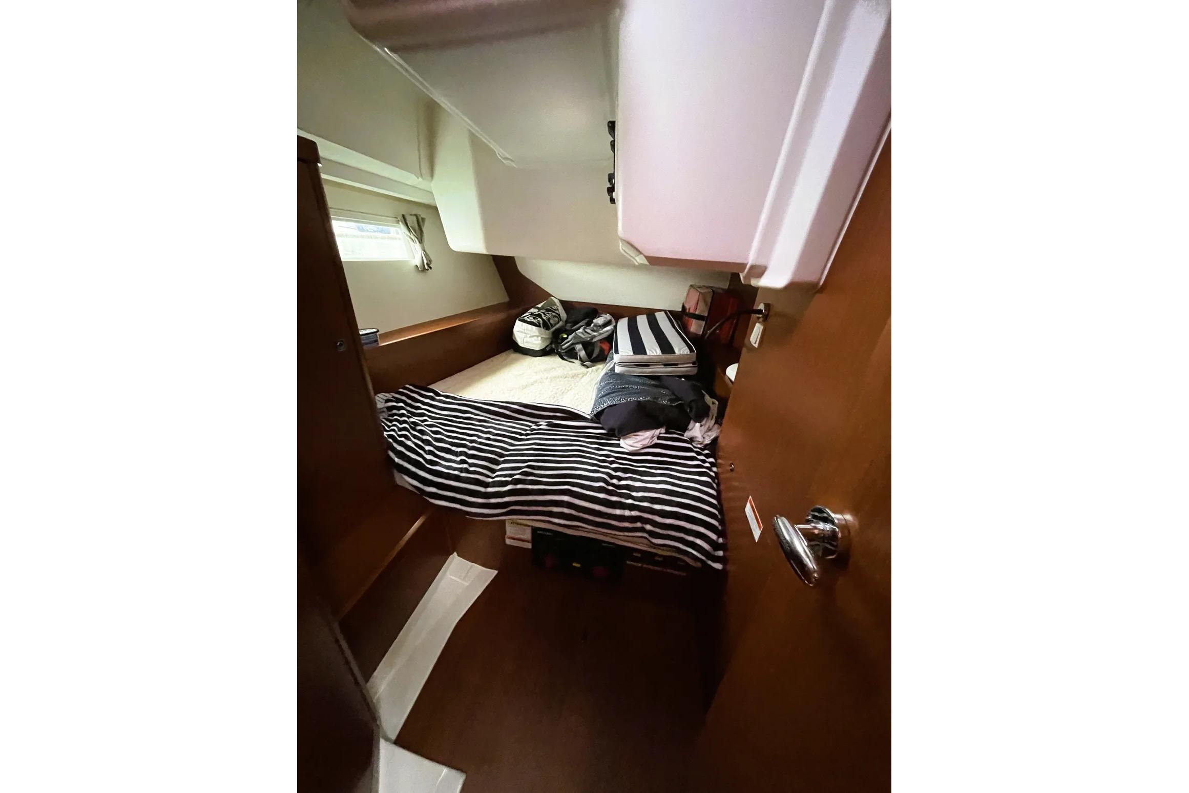 Cozy cabin interior of 2018 Beneteau Oceanis 45 sailboat with striped bedding.