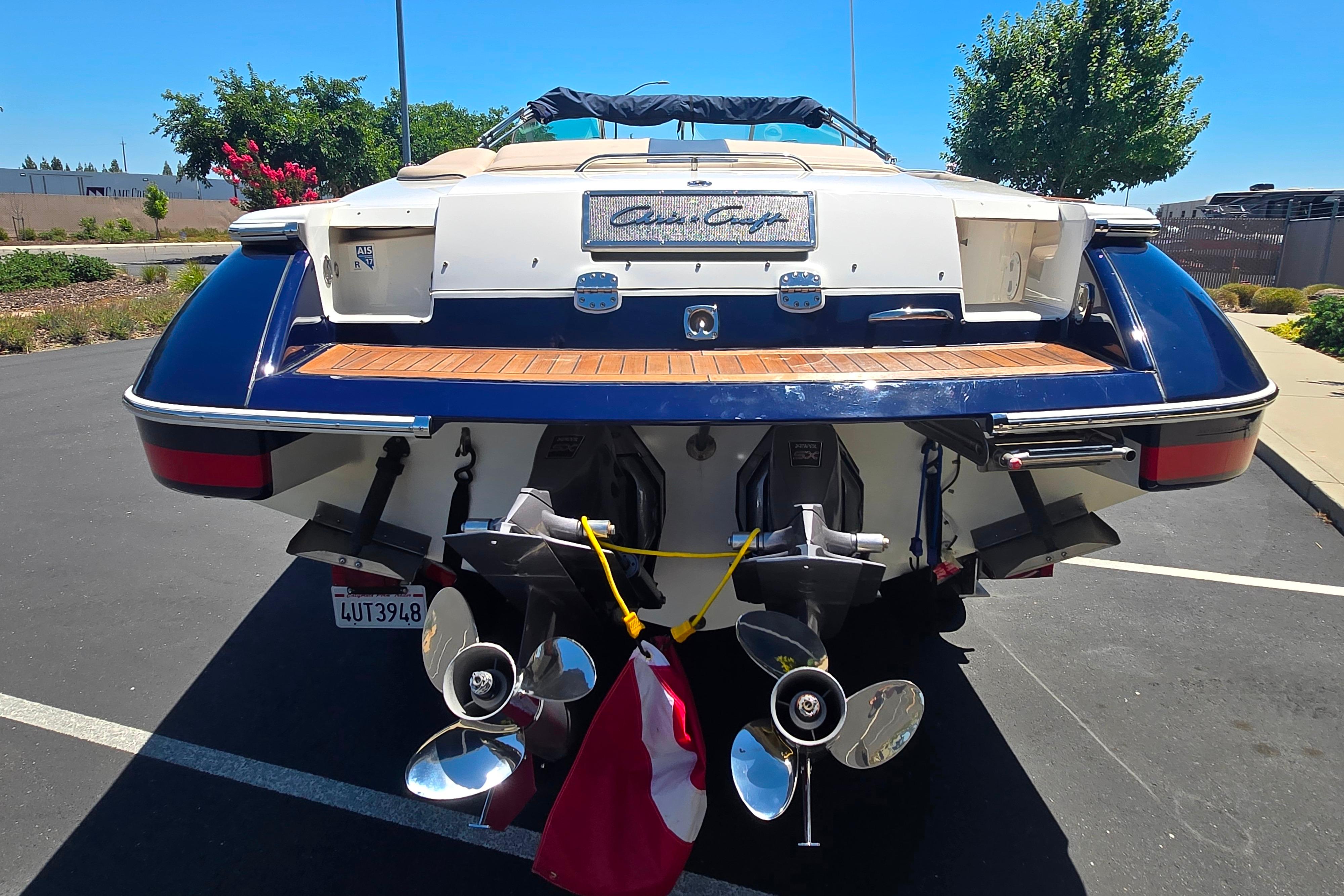 2002 Chris-Craft Launch 28 GT I/O boat, rear view with dual propellers, parked outdoors.
