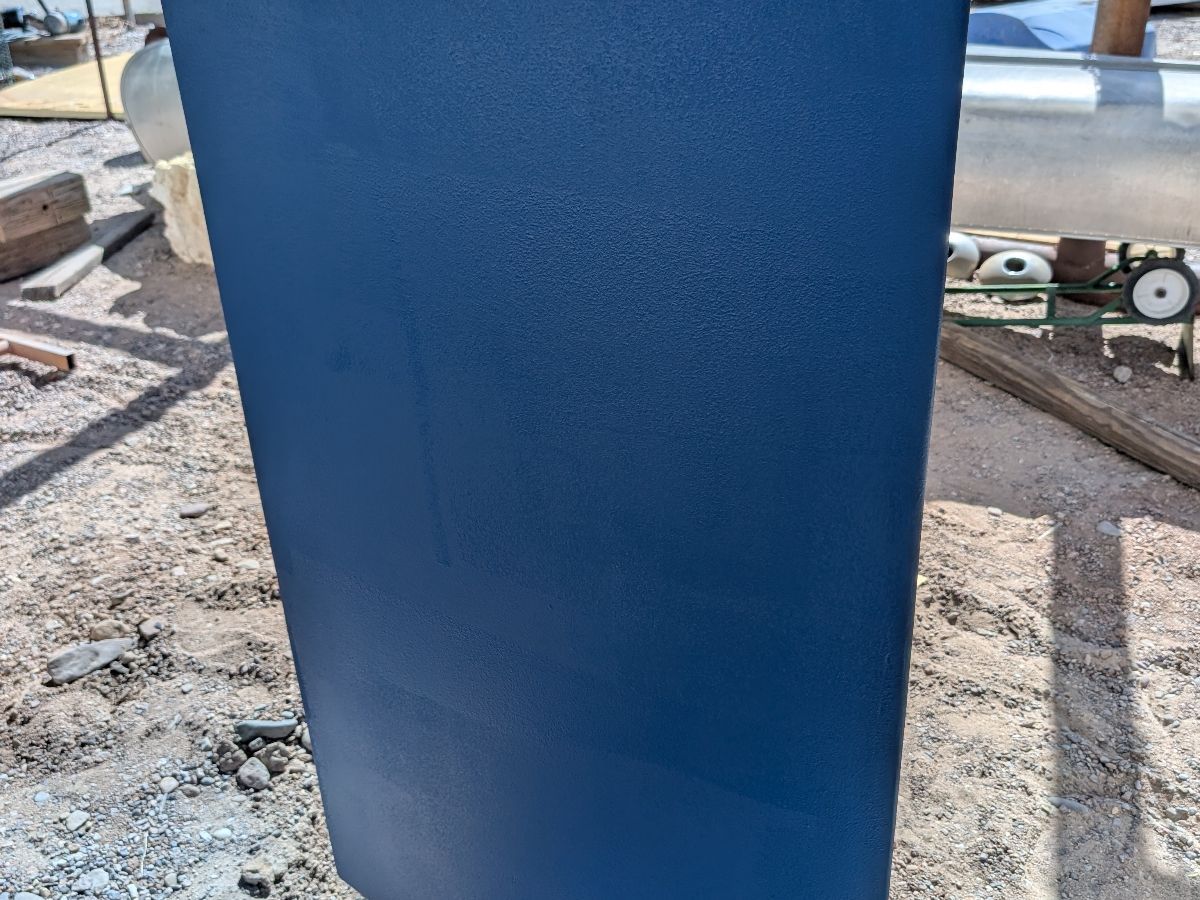 Close-up of a blue boat hull on dry ground.