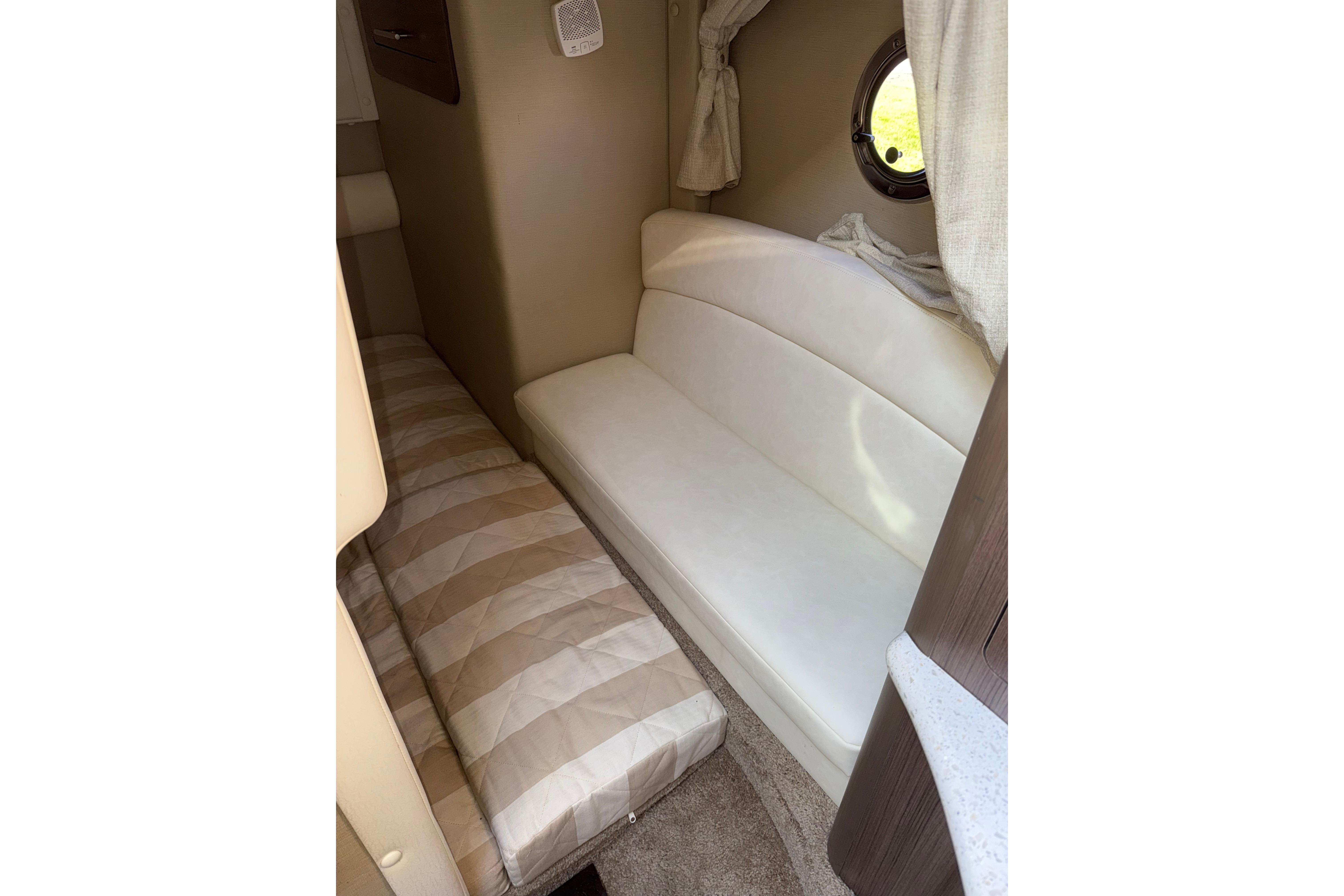 2019 Rinker EX 320 cabin interior with beige seating and porthole window.