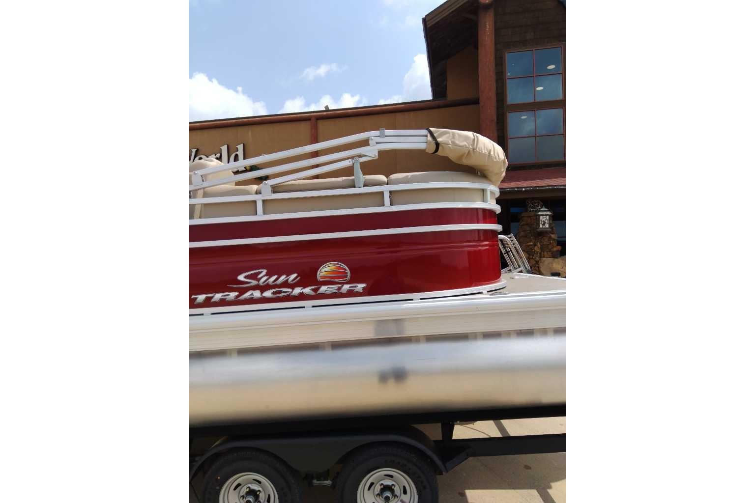 2025 Sun Tracker Party Barge 22 DLX pontoon boat with red exterior on trailer.