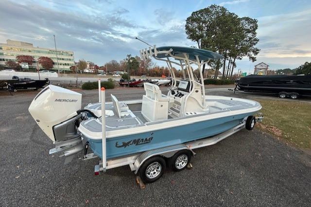 2025 Mako 24 APEX boat on trailer, featuring Mercury outboard motor, parked outdoors.