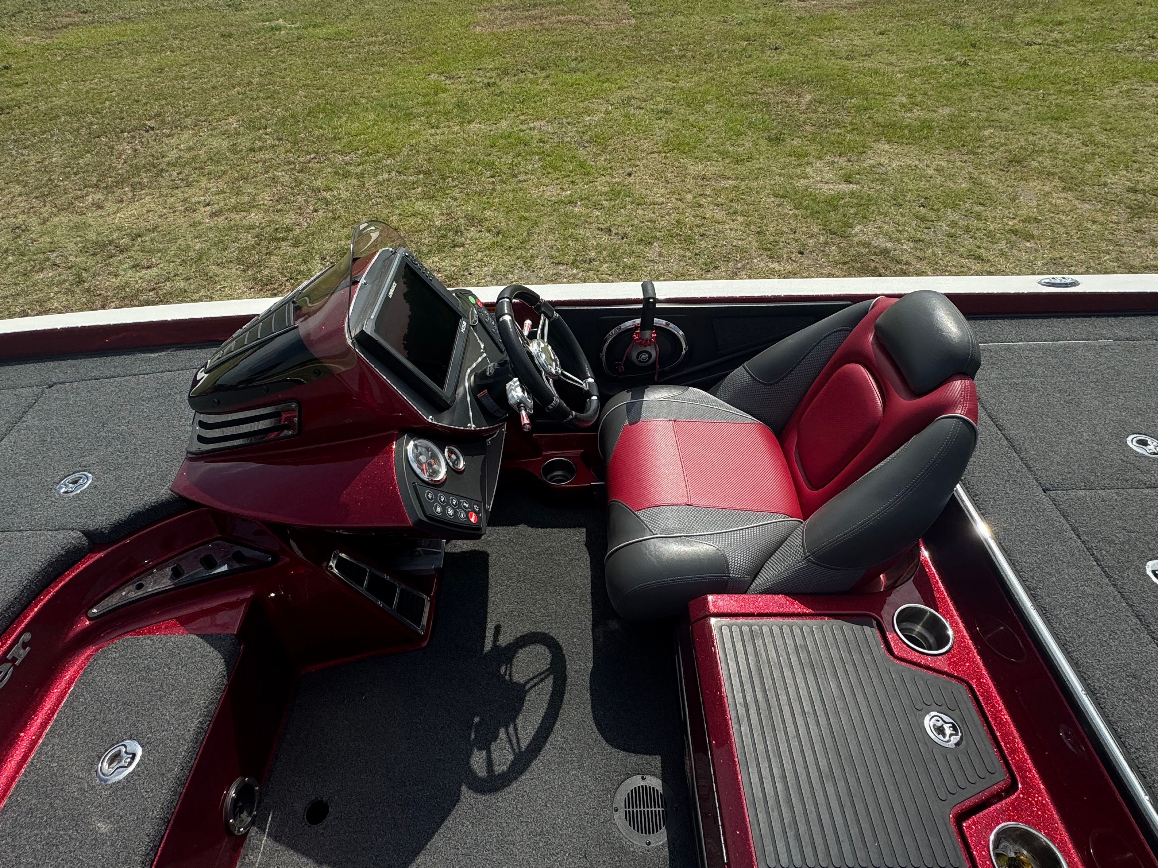 A Ranger 521C boat with red and black interior on dry grass.