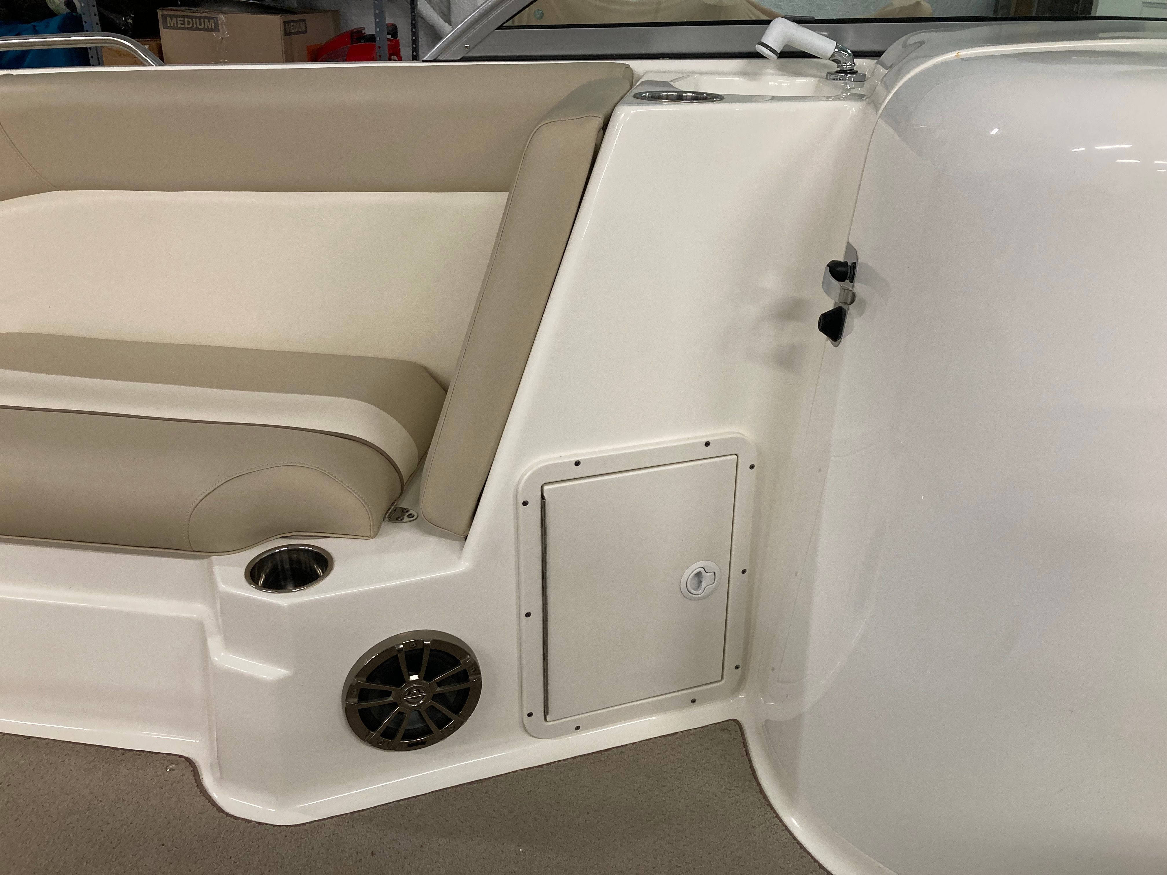 Interior of a boat with beige seating and a speaker.
