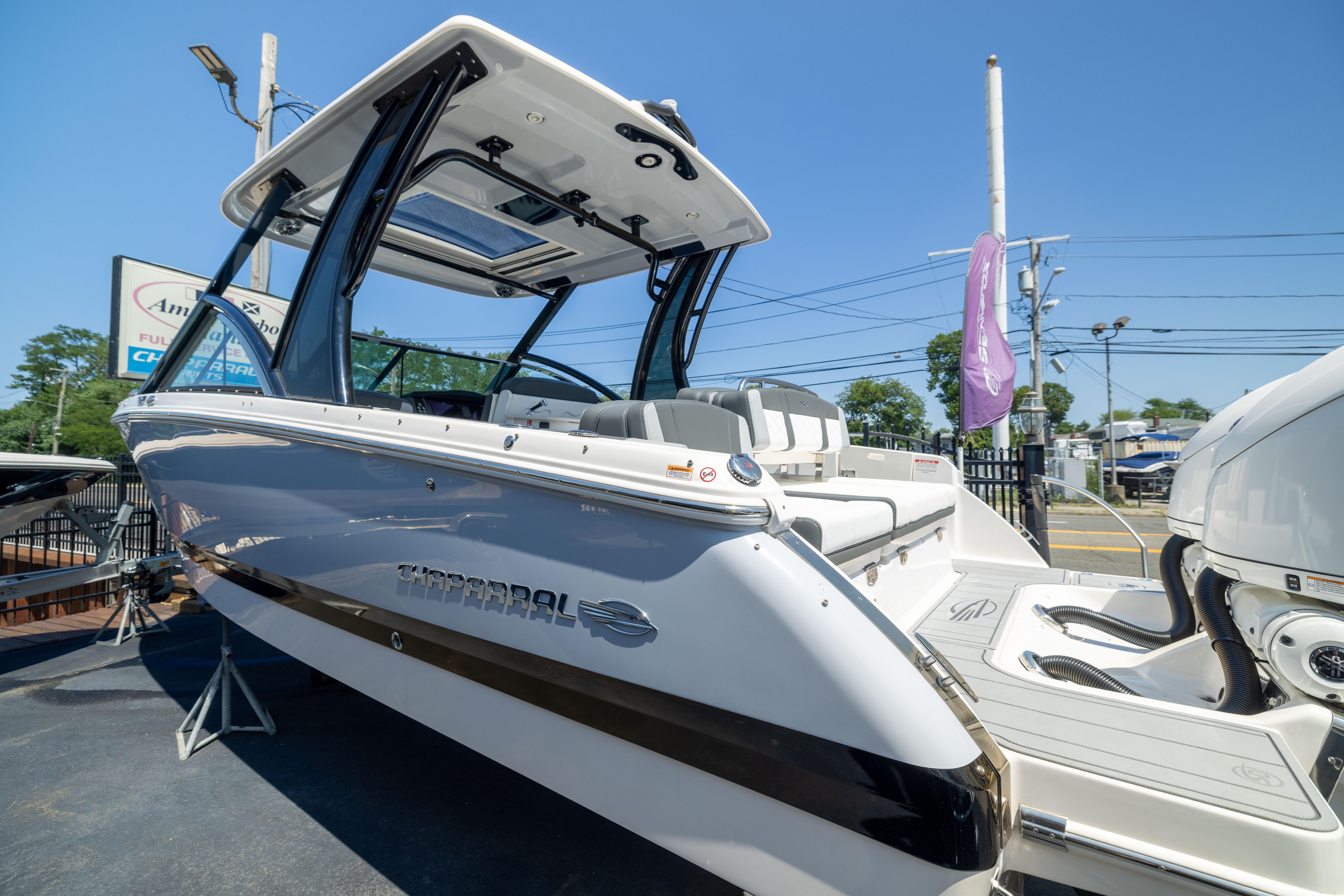 2026 Chaparral 310 OSX boat with sleek design, docked outdoors under clear blue sky.