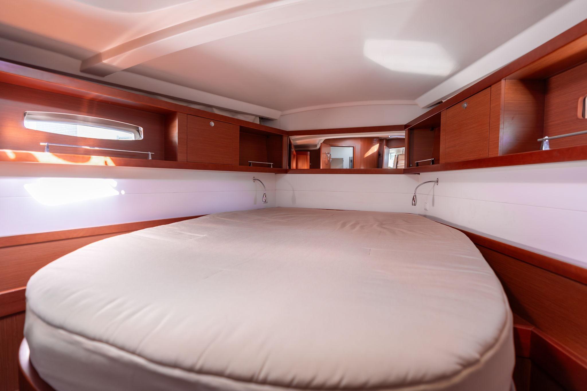 Luxurious cabin interior of 2013 Beneteau Oceanis 50 yacht with cozy bed and wooden finish.