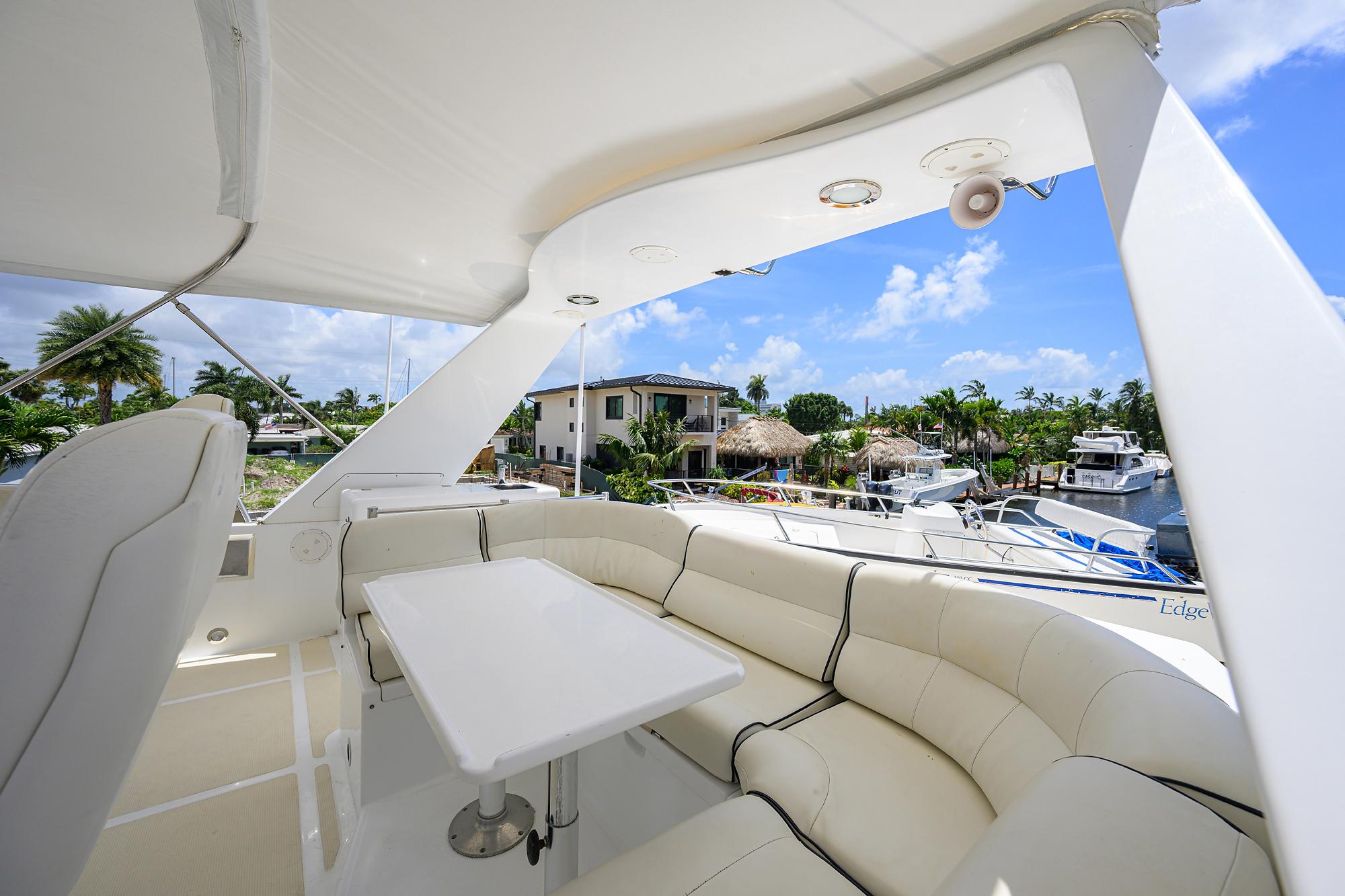Luxurious 2001 Ocean Alexander 602 yacht deck with white seating and table, marina view.