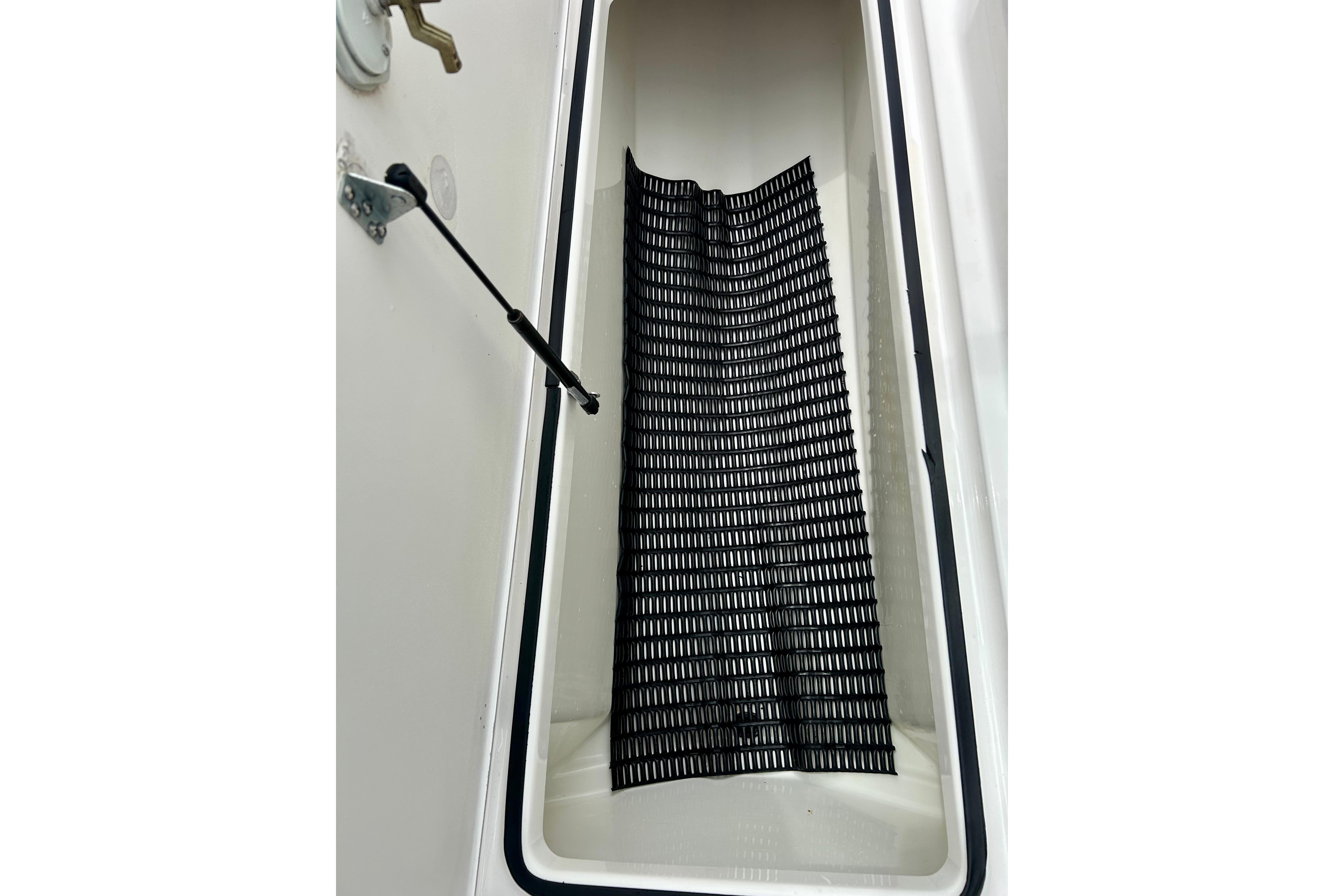 Storage compartment of a 2015 Yamaha AR210 boat with a black mat inside.