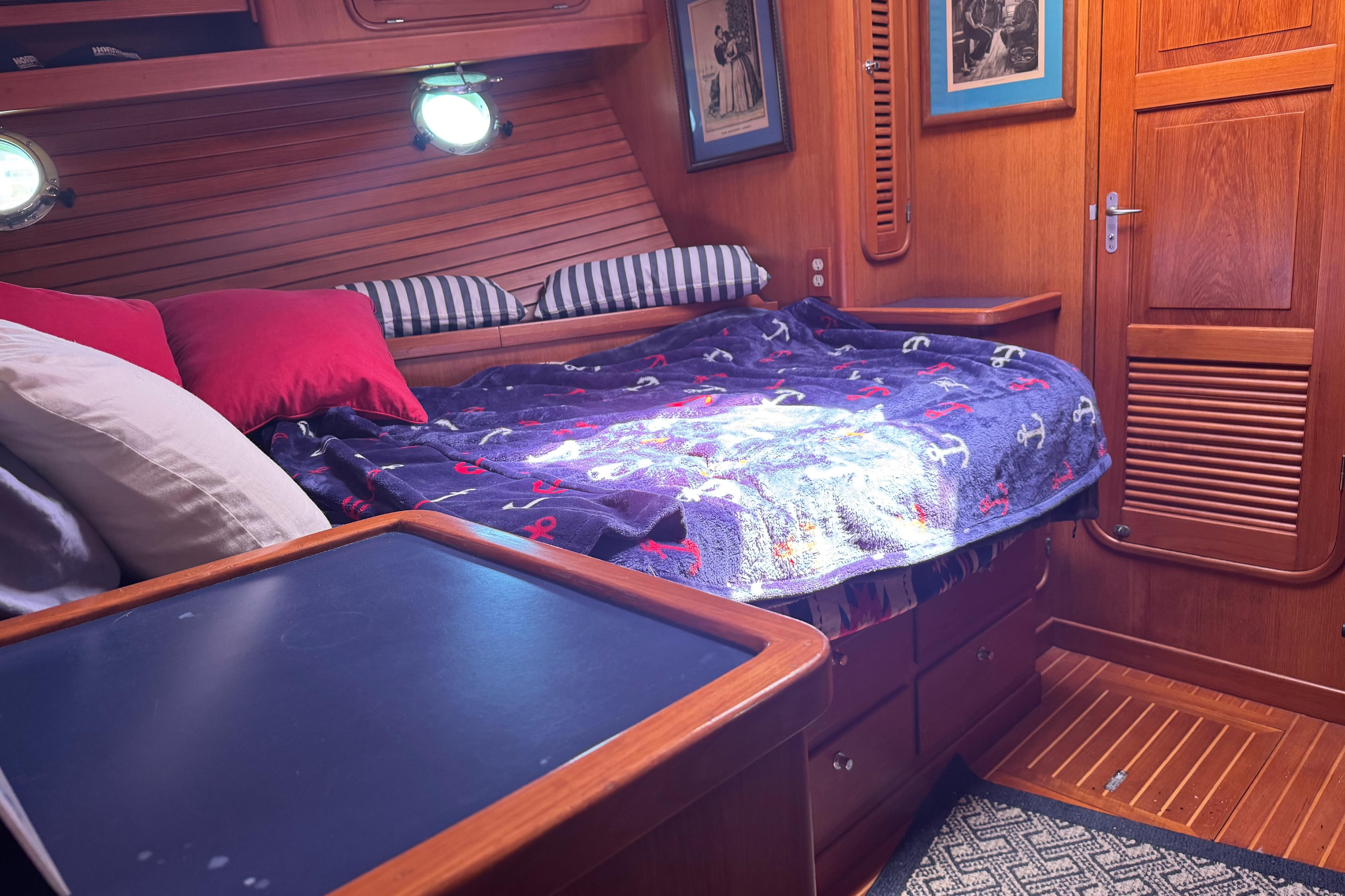 Cozy cabin interior of a 1995 Nordhavn 46 yacht with nautical-themed bedding.