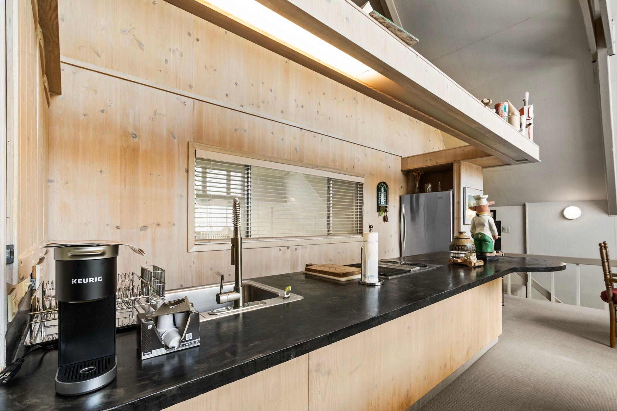 Modern kitchen in 1976 custom boathouse with sleek countertops and Keurig coffee maker.