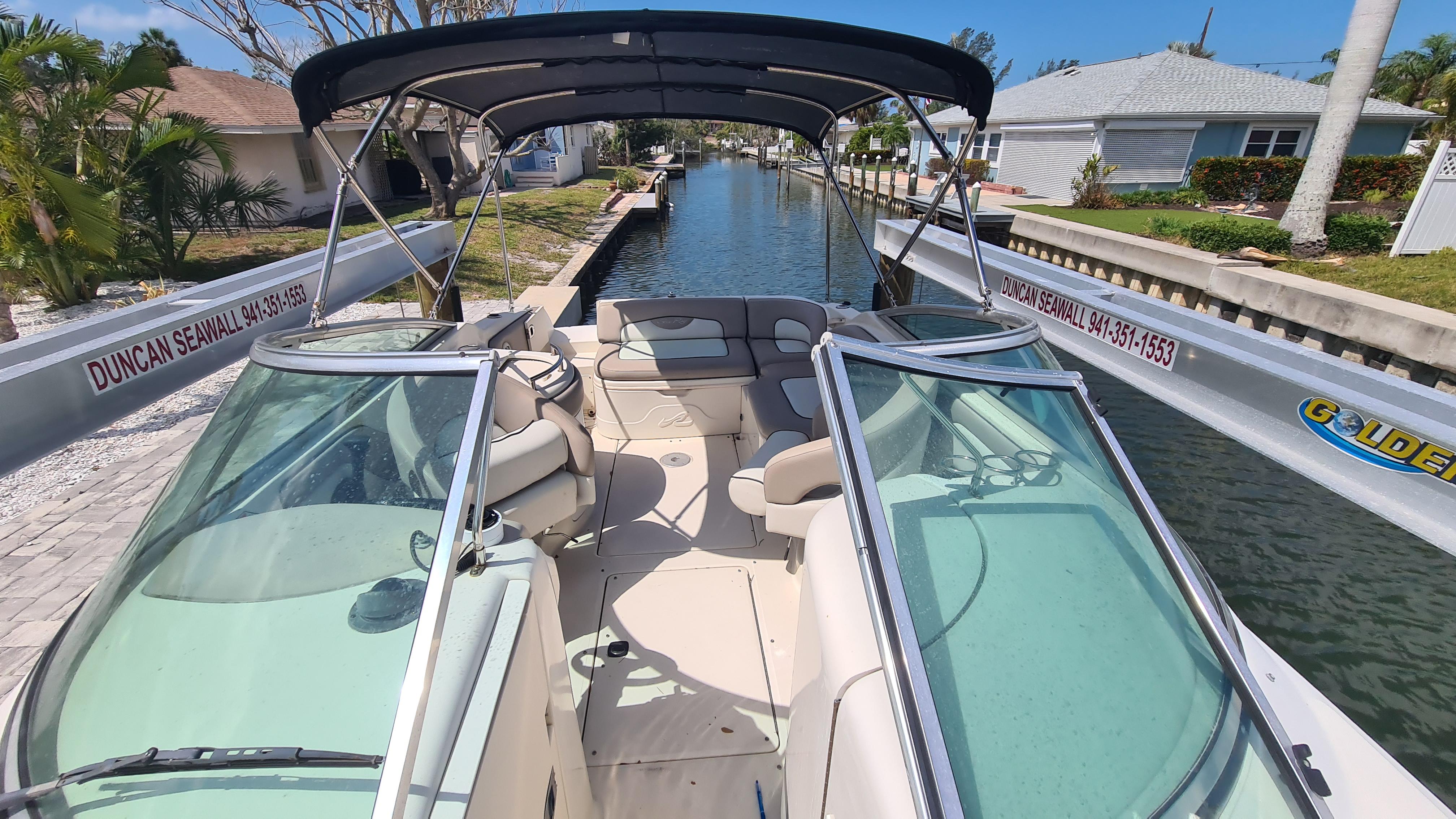2004 Sea Ray 270 Sundeck boat docked in a canal, featuring spacious seating and canopy.