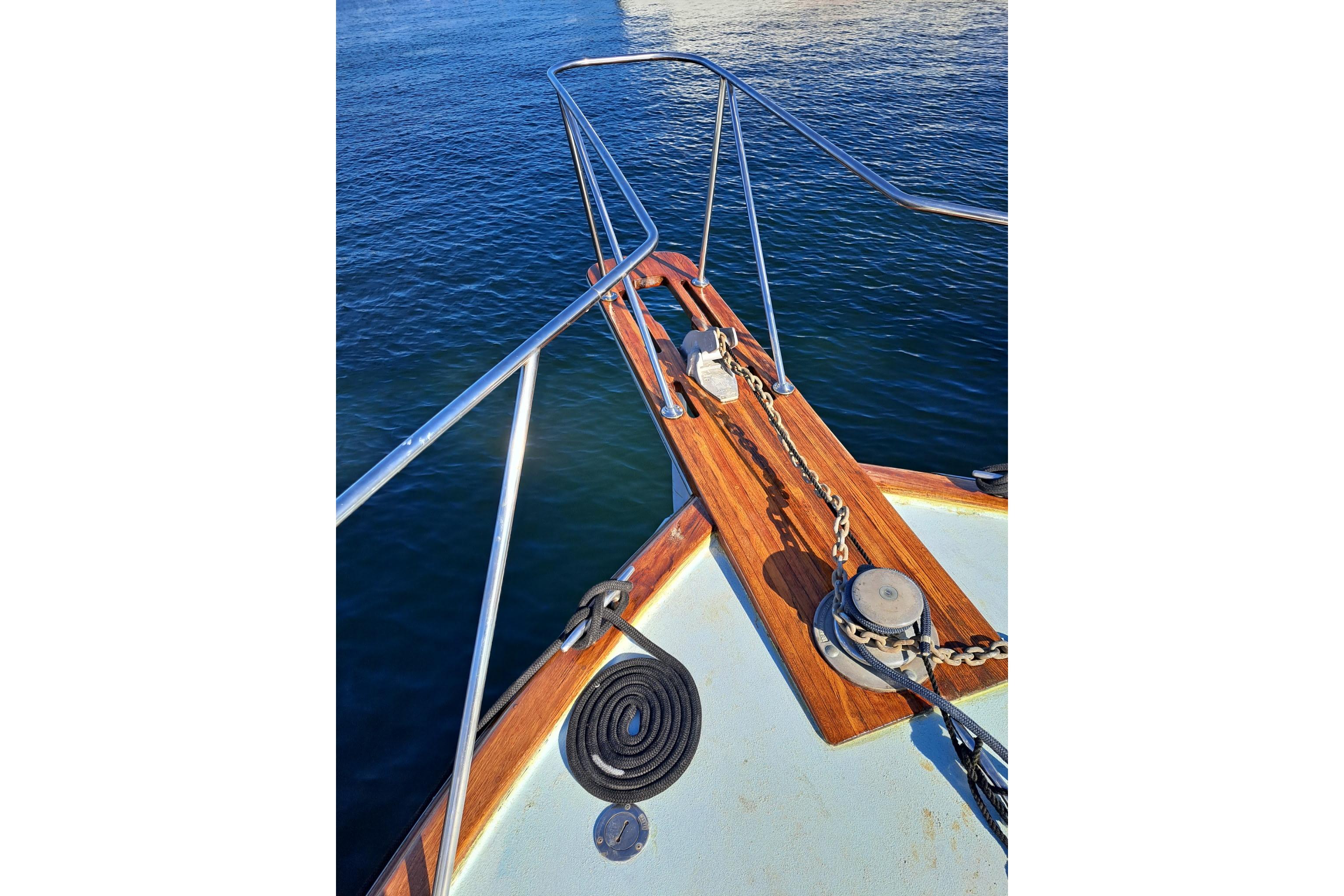 Bow of 1988 Ocean Yachts 48 Super Sport on calm water, featuring anchor chain and railing.