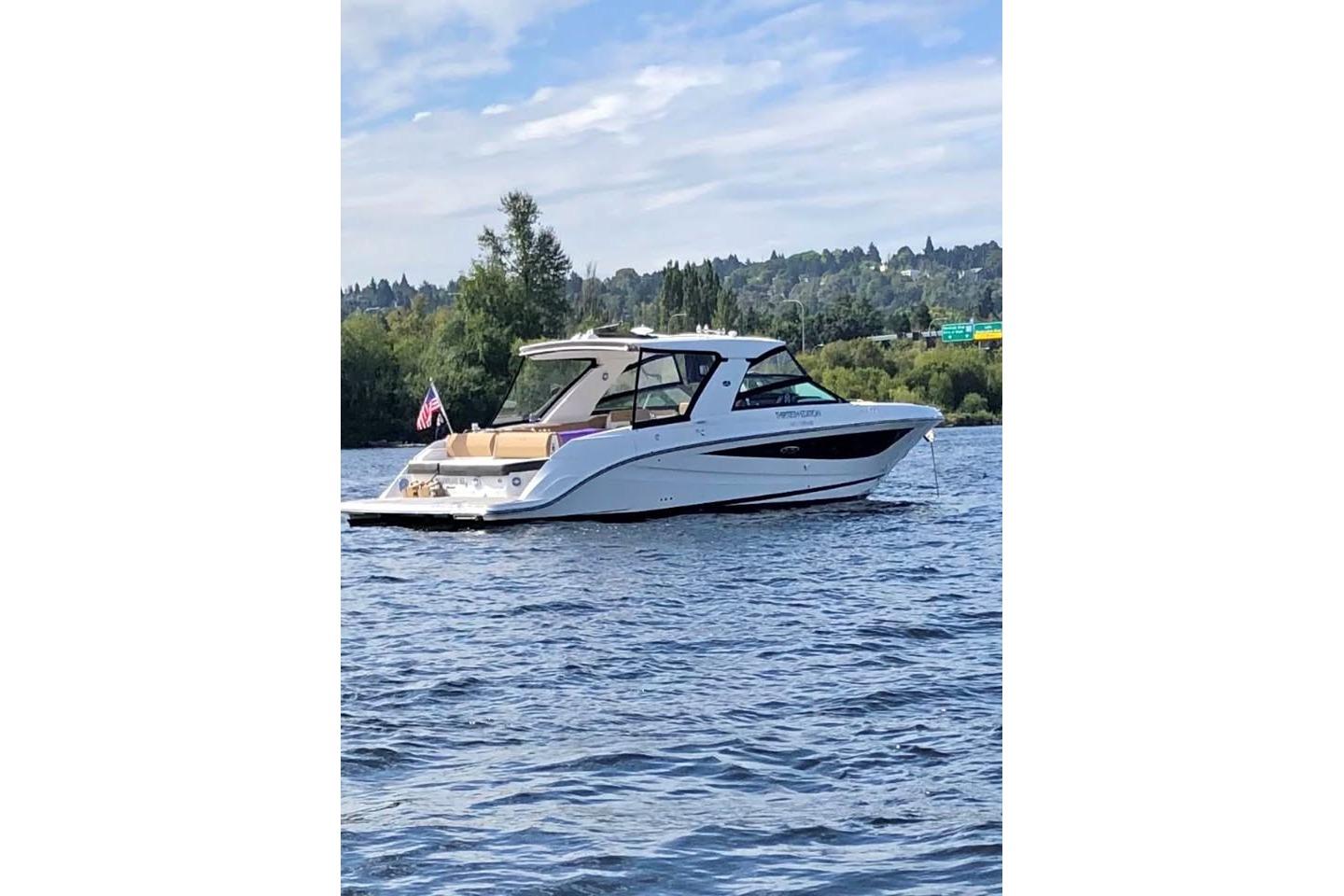 2018 Sea Ray SLX 400 boat on a scenic lake with lush greenery.