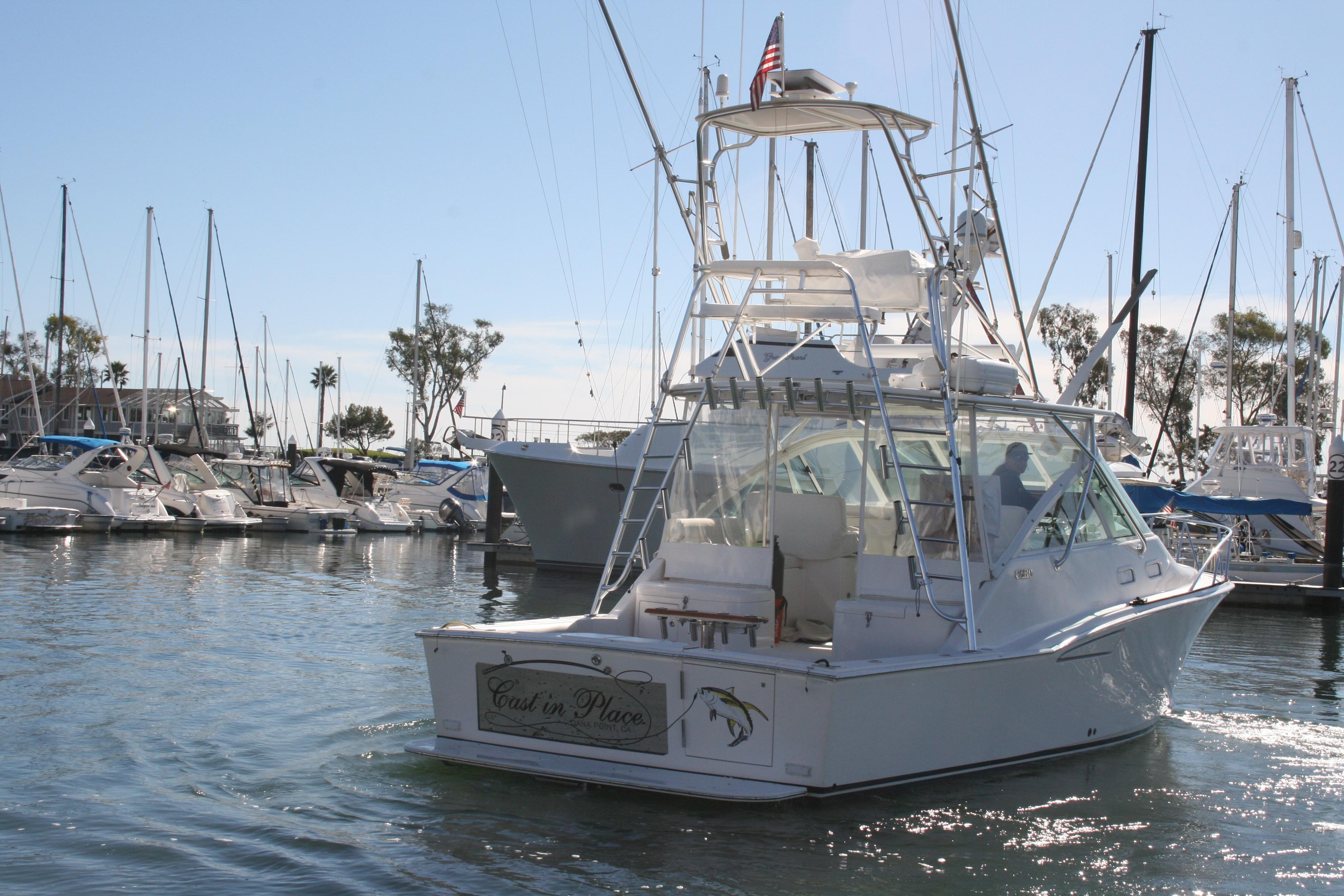 2005 Cabo 35 Express yacht docked in a marina with sailboats.