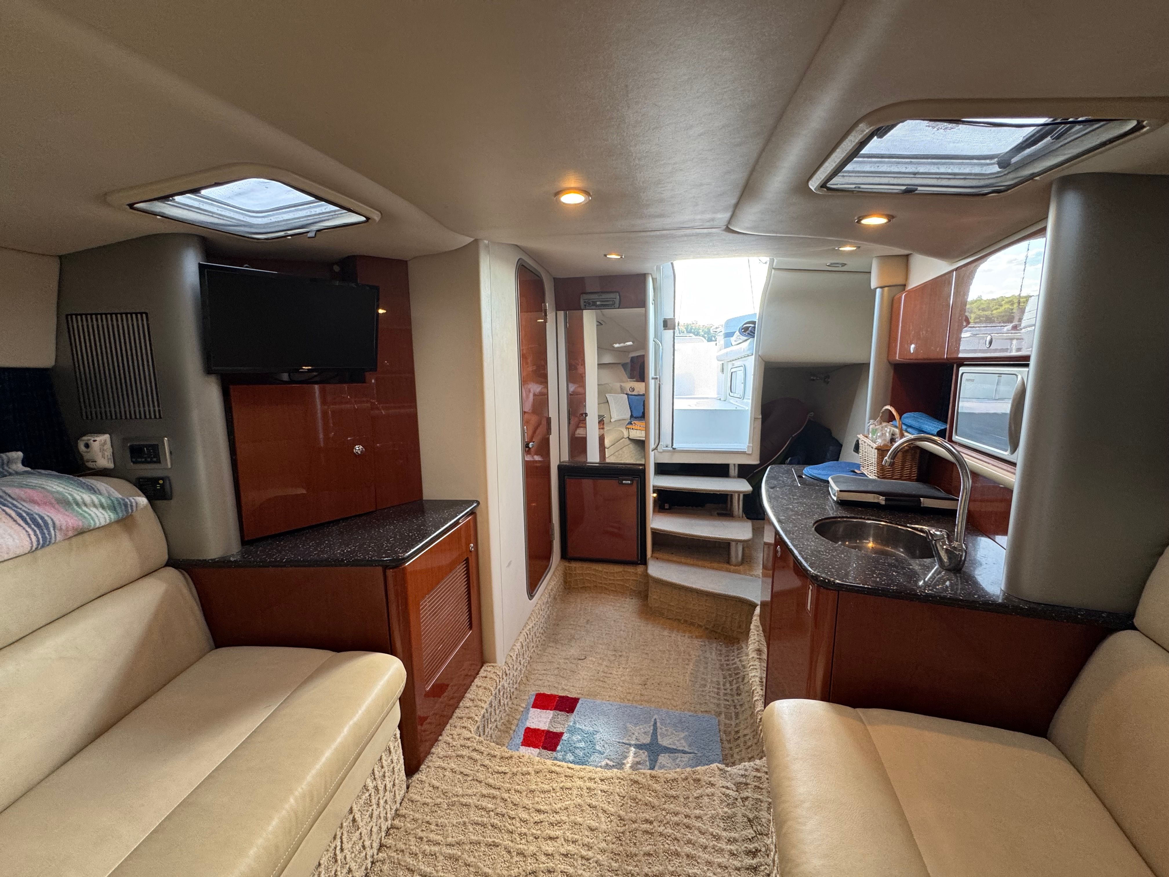 Interior of a luxury yacht with seating area, TV, and kitchenette.