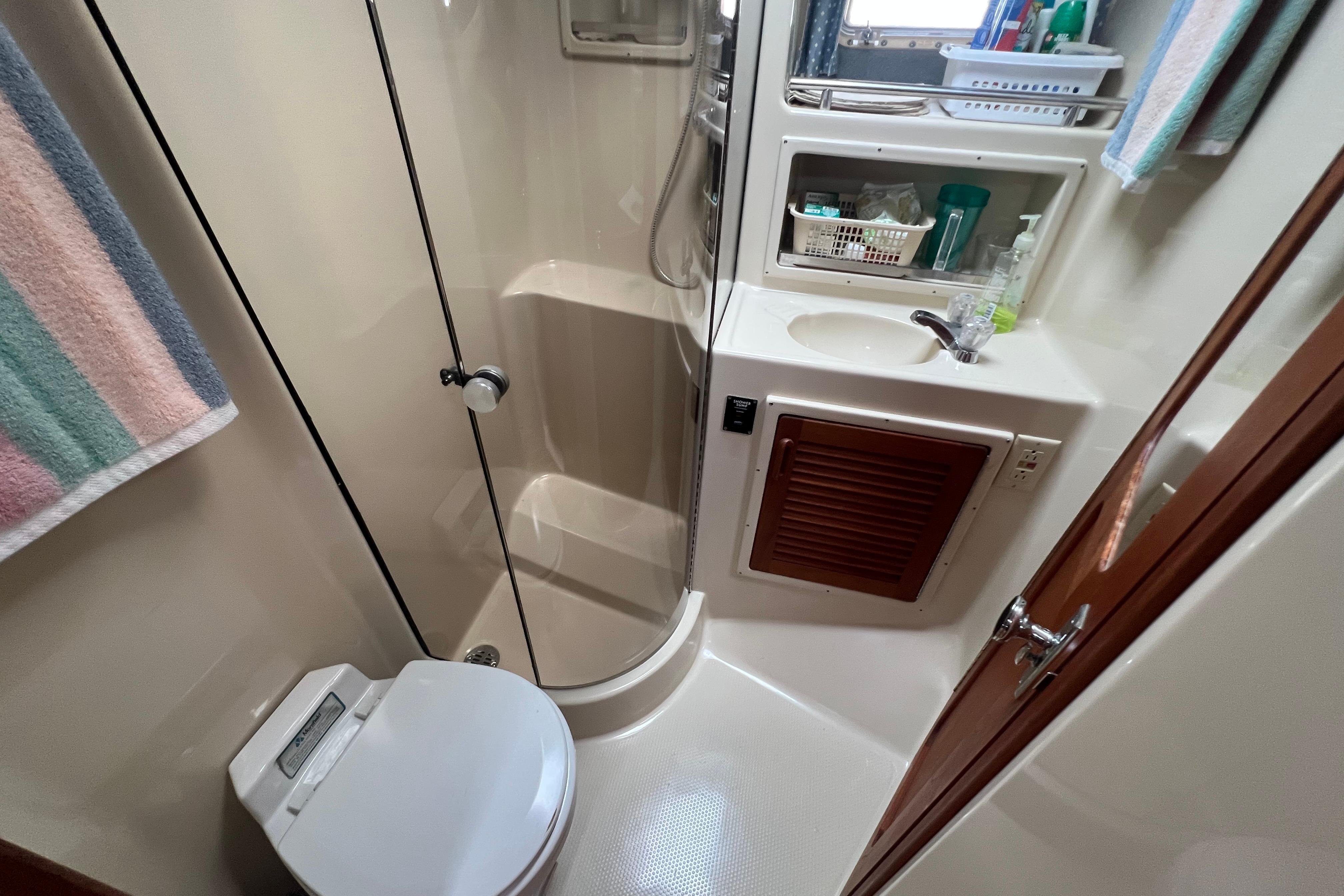 Compact bathroom in a 1985 Tiara 36 OPEN yacht with shower, toilet, and sink.