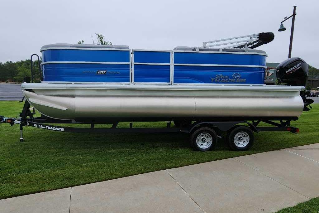2026 Sun Tracker Party Barge 20 DLX pontoon boat on trailer, parked on grass.
