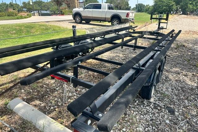 Trailer for 2021 Bennington L Bowrider 25 Quad Bench on gravel lot.