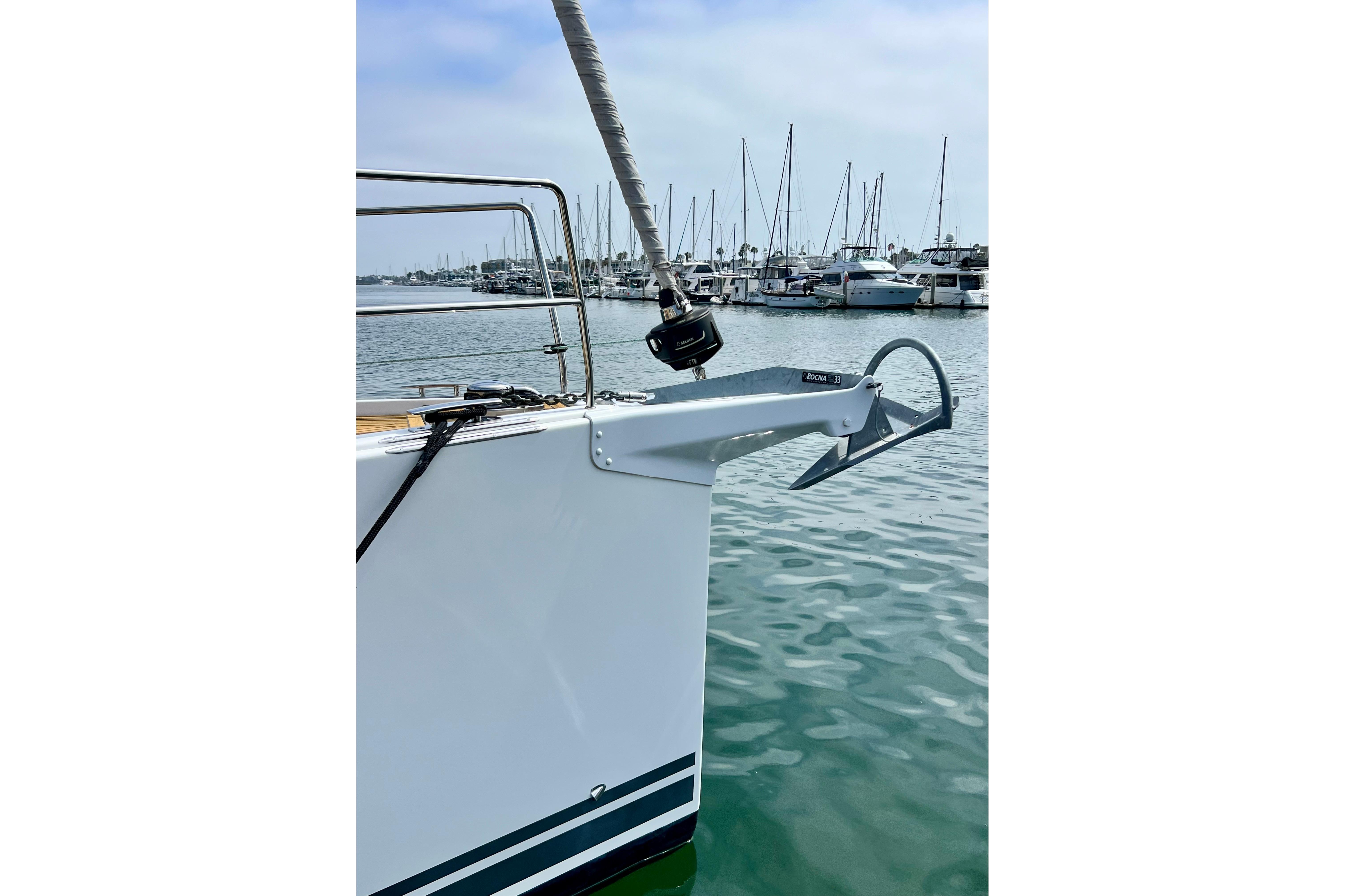 Bow of 2016 Hanse 455 yacht with anchor, docked in marina.
