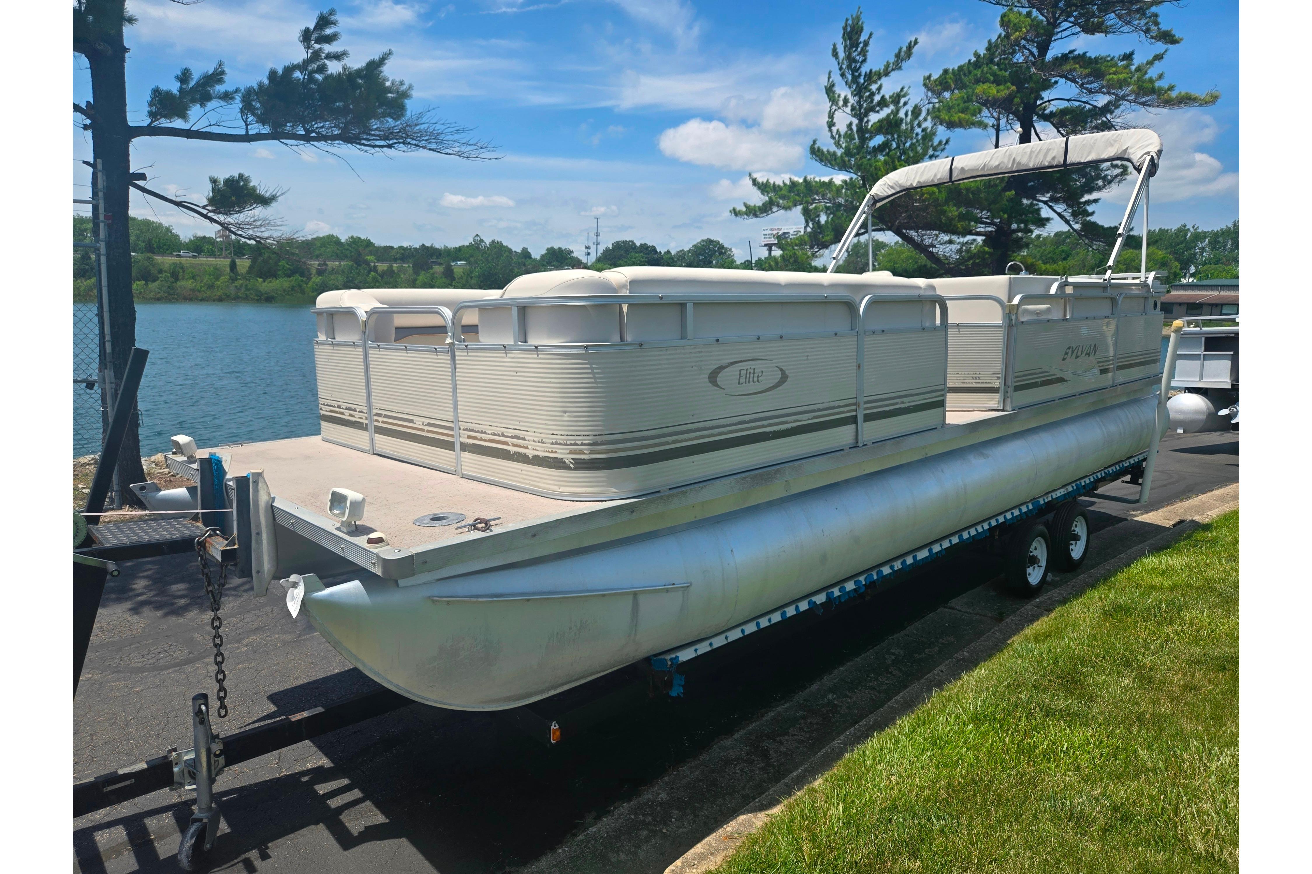 2000 Sylvan 824 Elite Cruise pontoon boat on trailer by a lake.