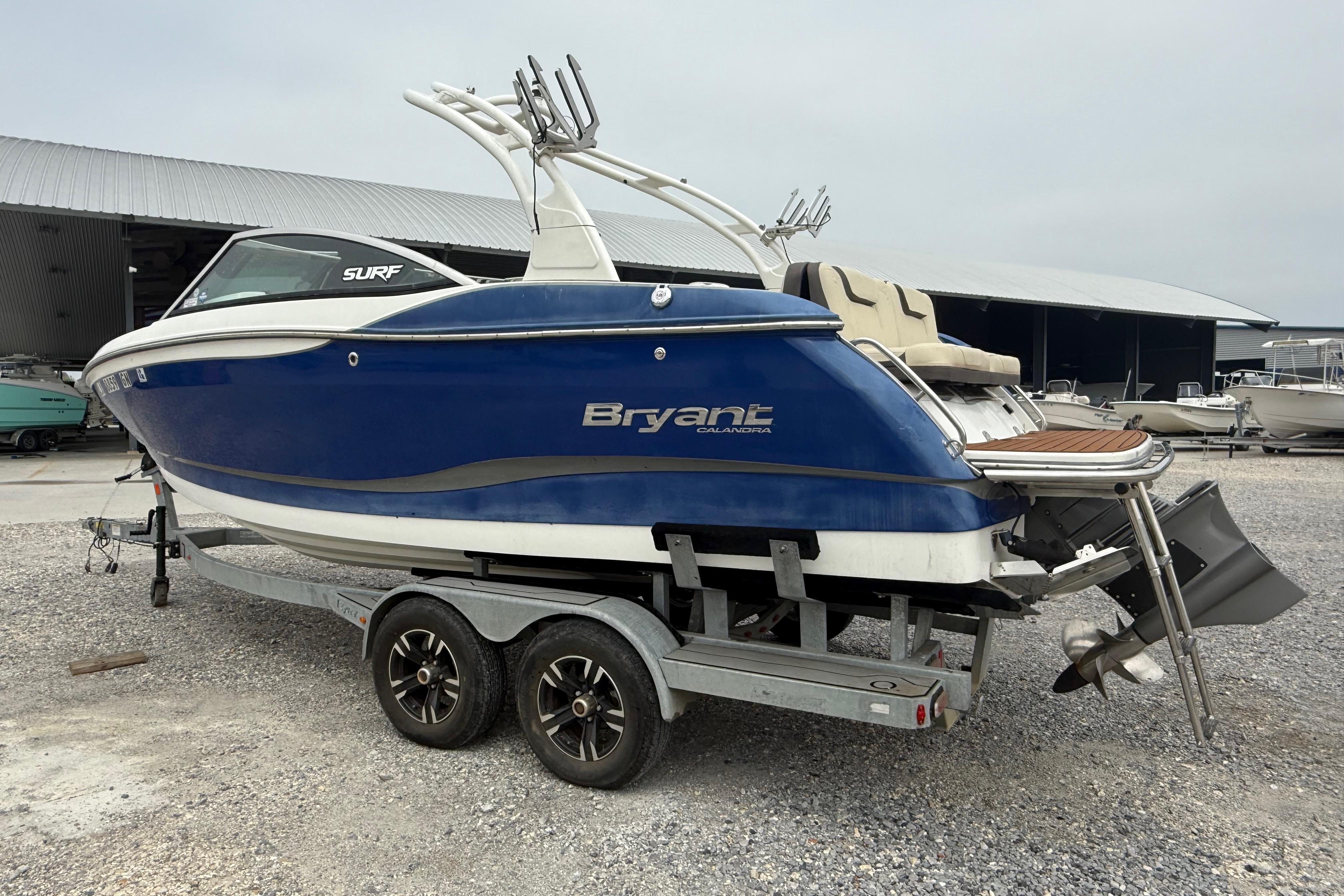 2018 Bryant Calandra boat on trailer, blue and white, parked near storage facility.