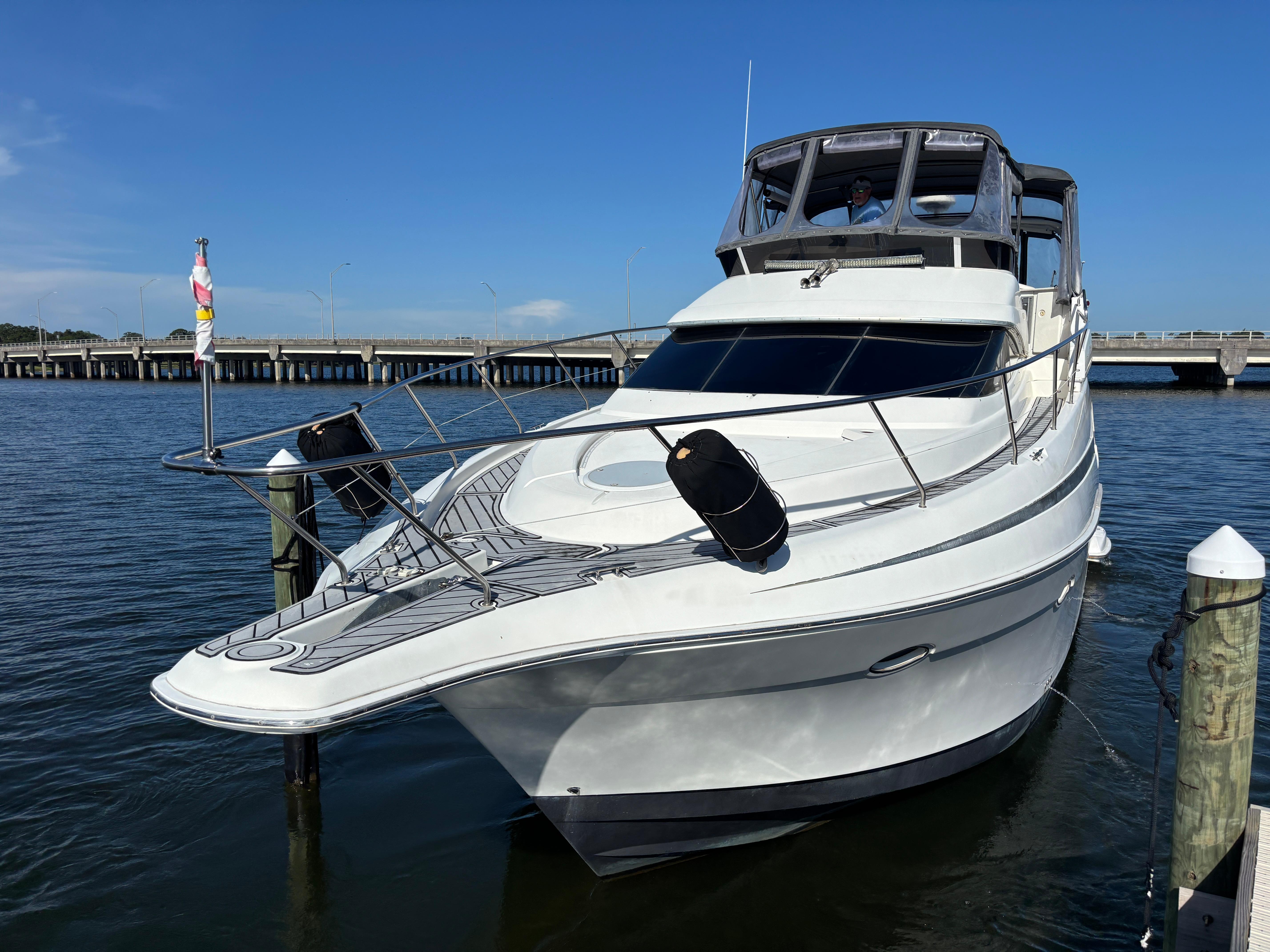 2001 Silverton 410 Sport Bridge yacht docked by a pier under clear blue skies.
