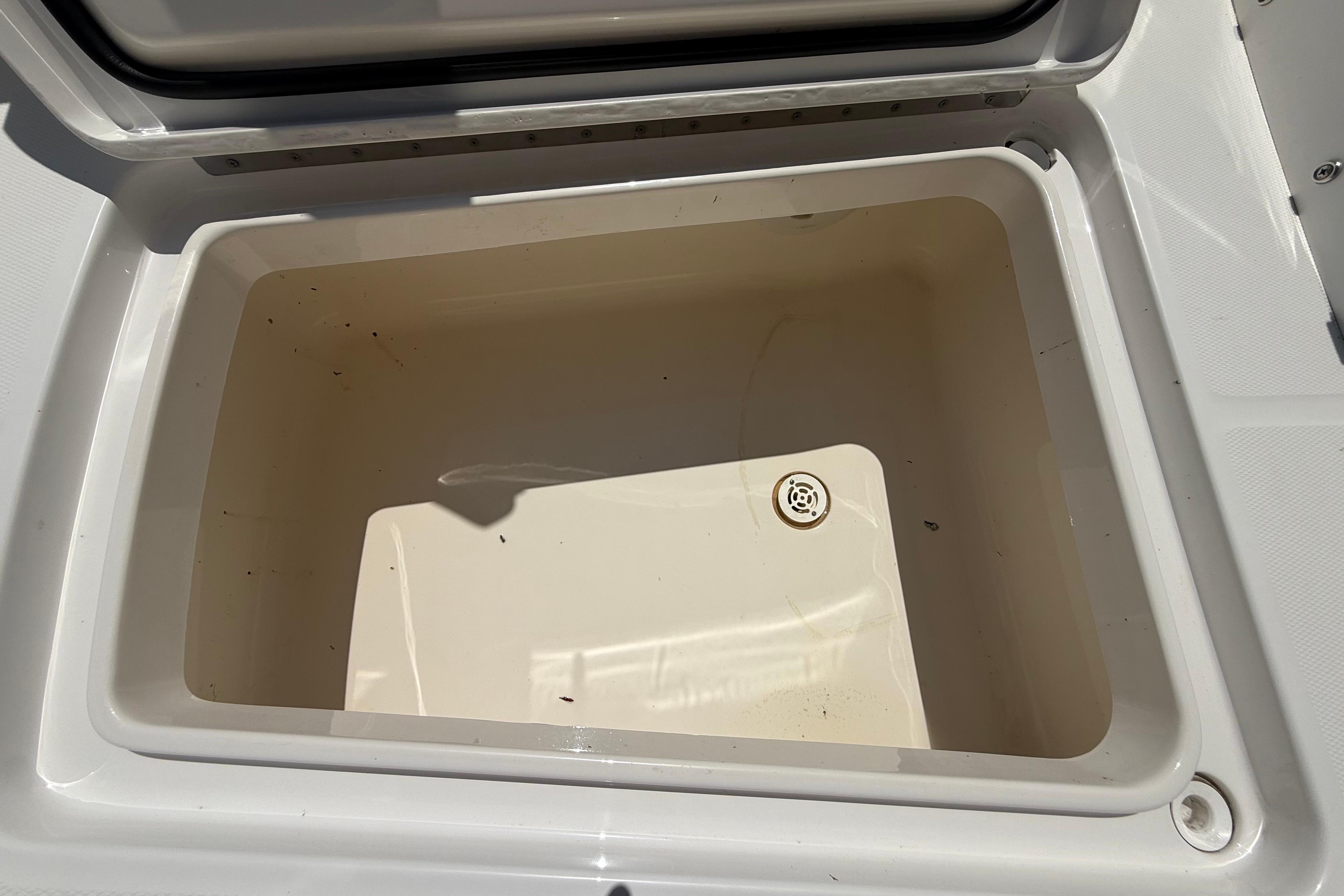 Open storage compartment on 2023 Regulator 26XO boat, featuring a drain plug.