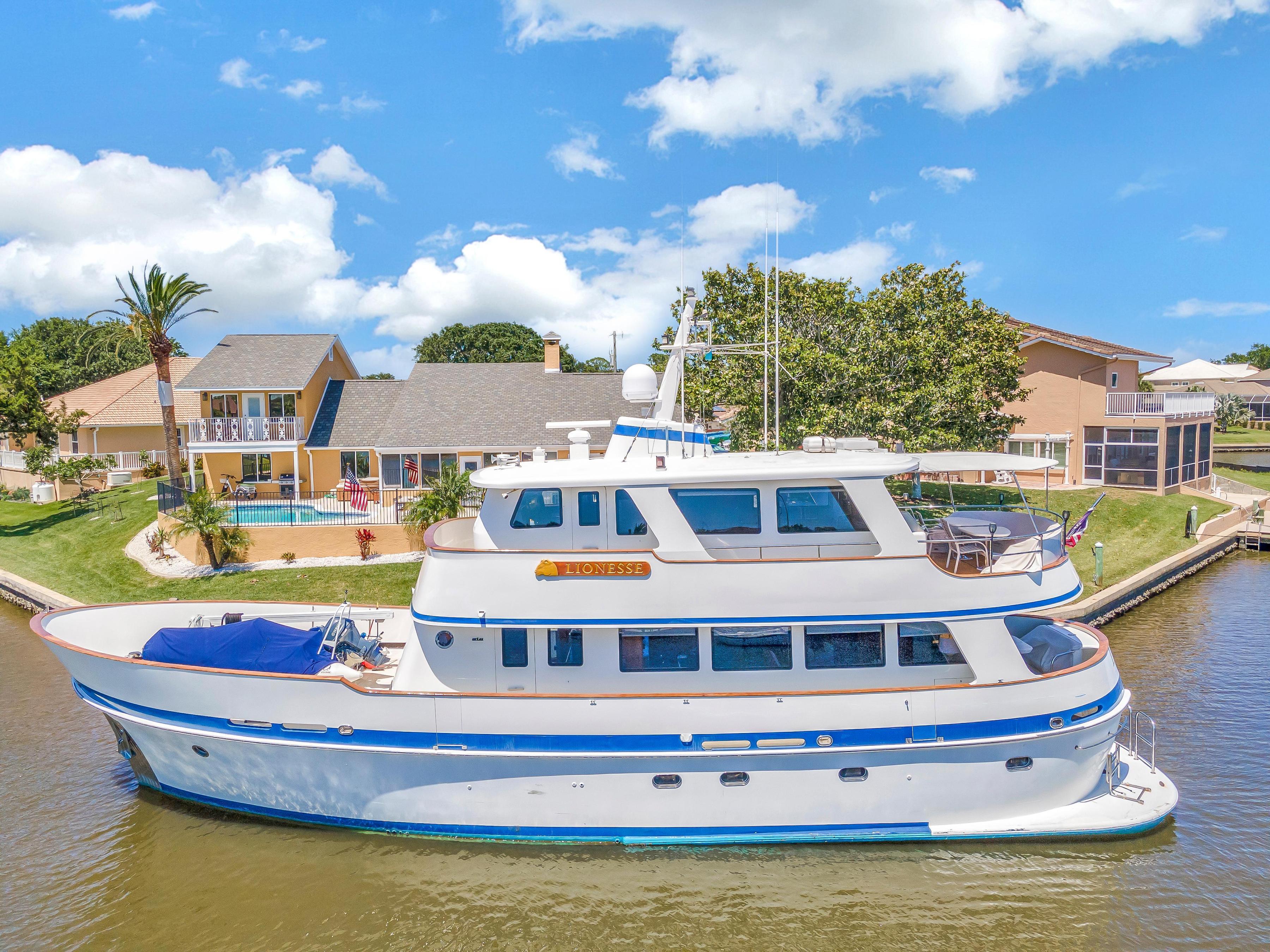 Cheoy Lee Expedition 70 yacht, 2001 model, docked near waterfront homes under a clear blue sky.