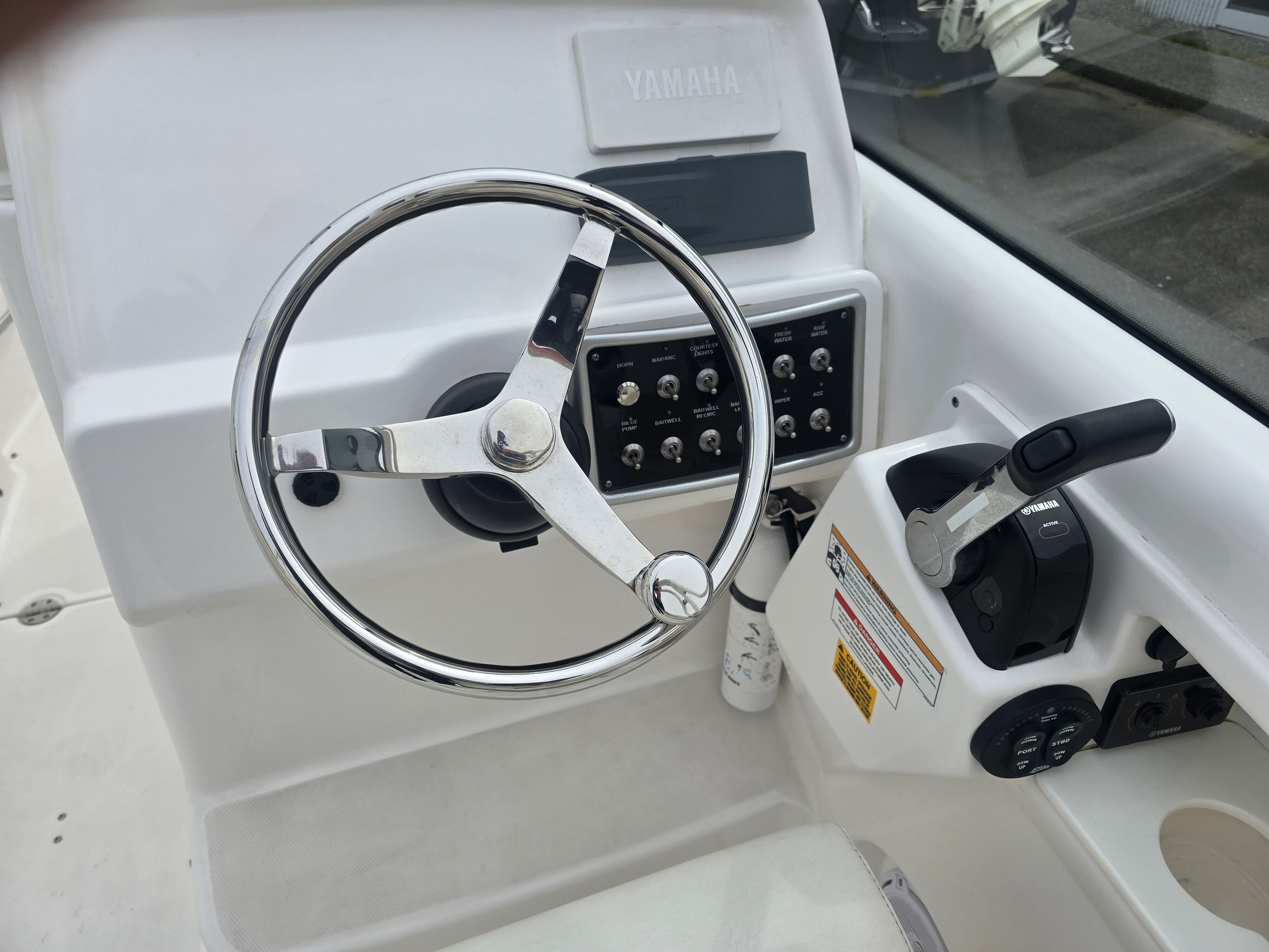 Helm of an Everglades 230 Dual Console boat with steering wheel and throttle control.