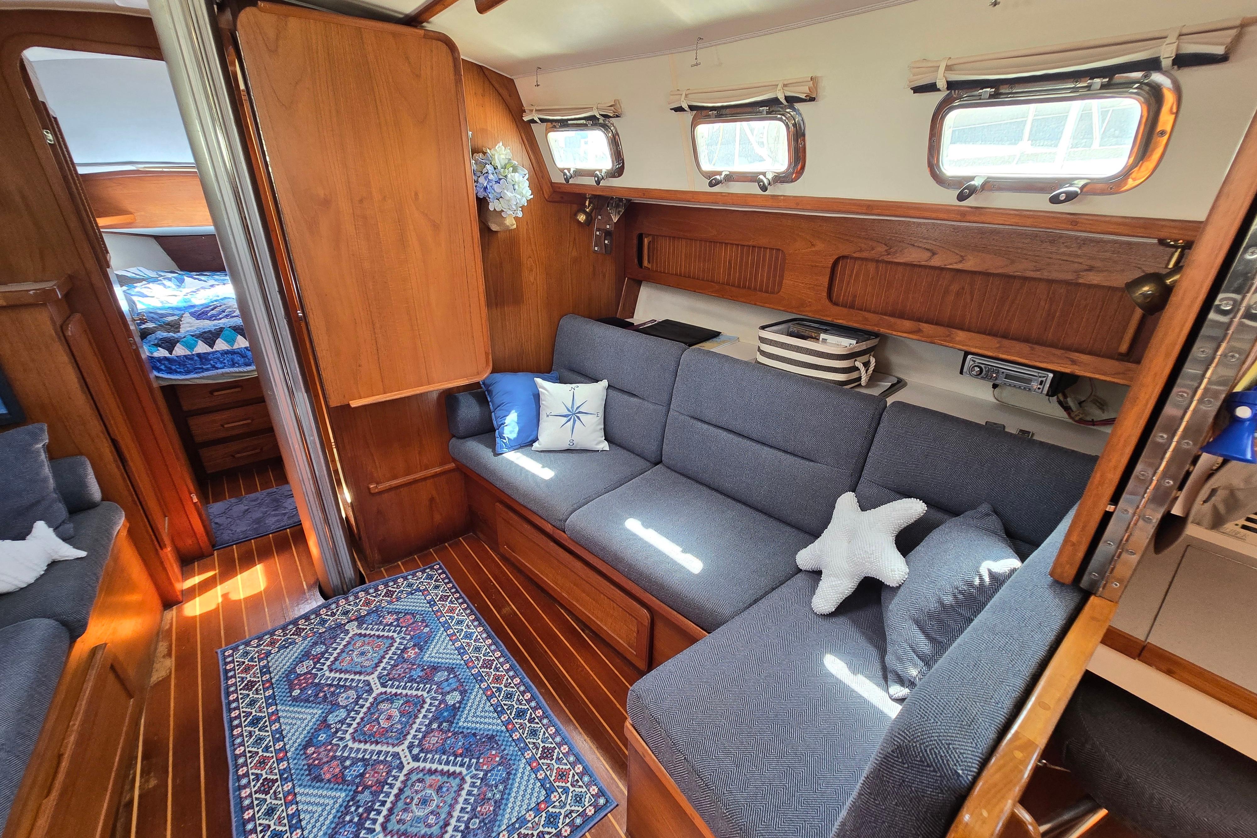 Cozy 1993 Caliber 35 yacht interior with blue seating, wooden accents, and nautical decor.