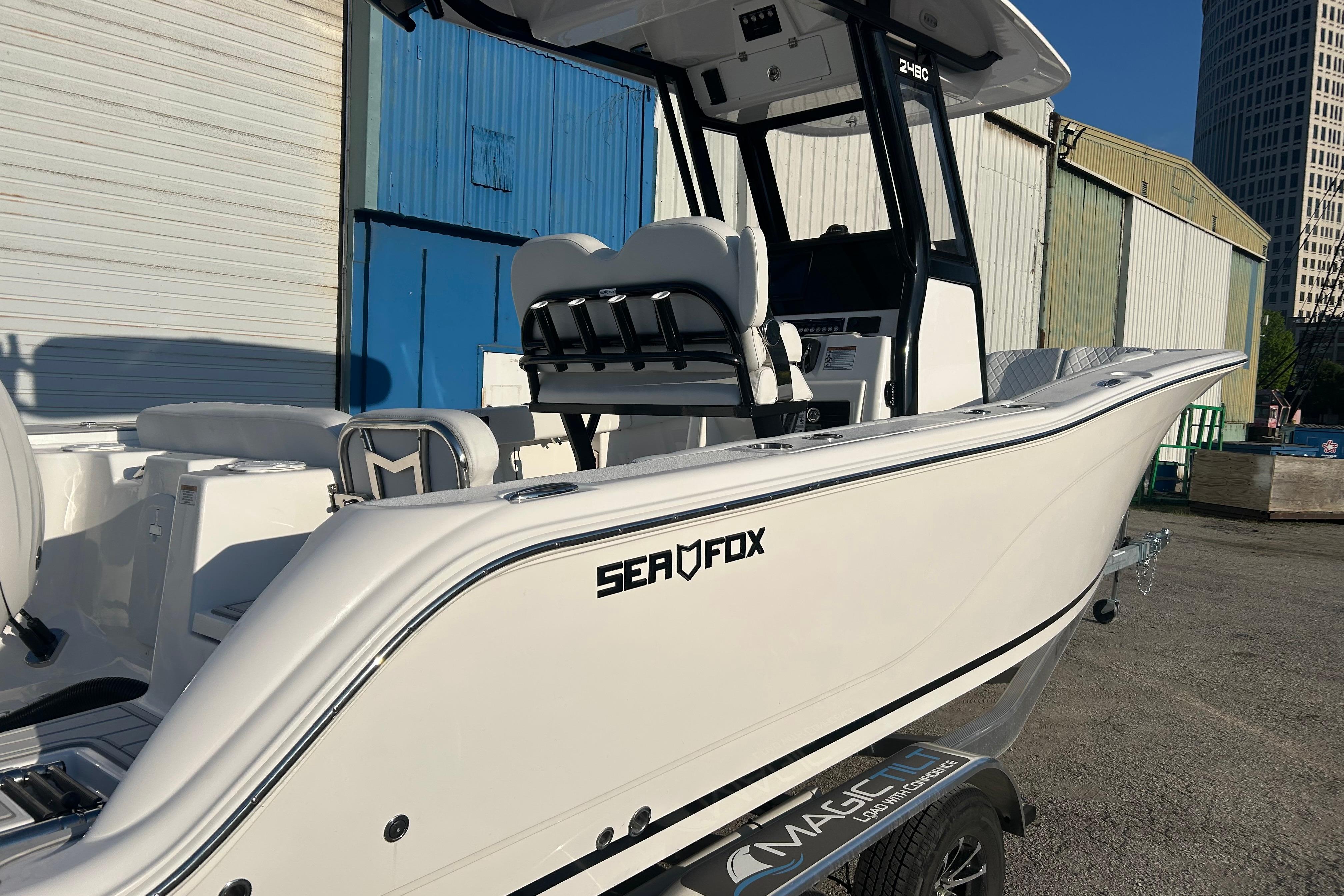 2026 Sea Fox 248 Commander boat on trailer, side view, near industrial buildings.