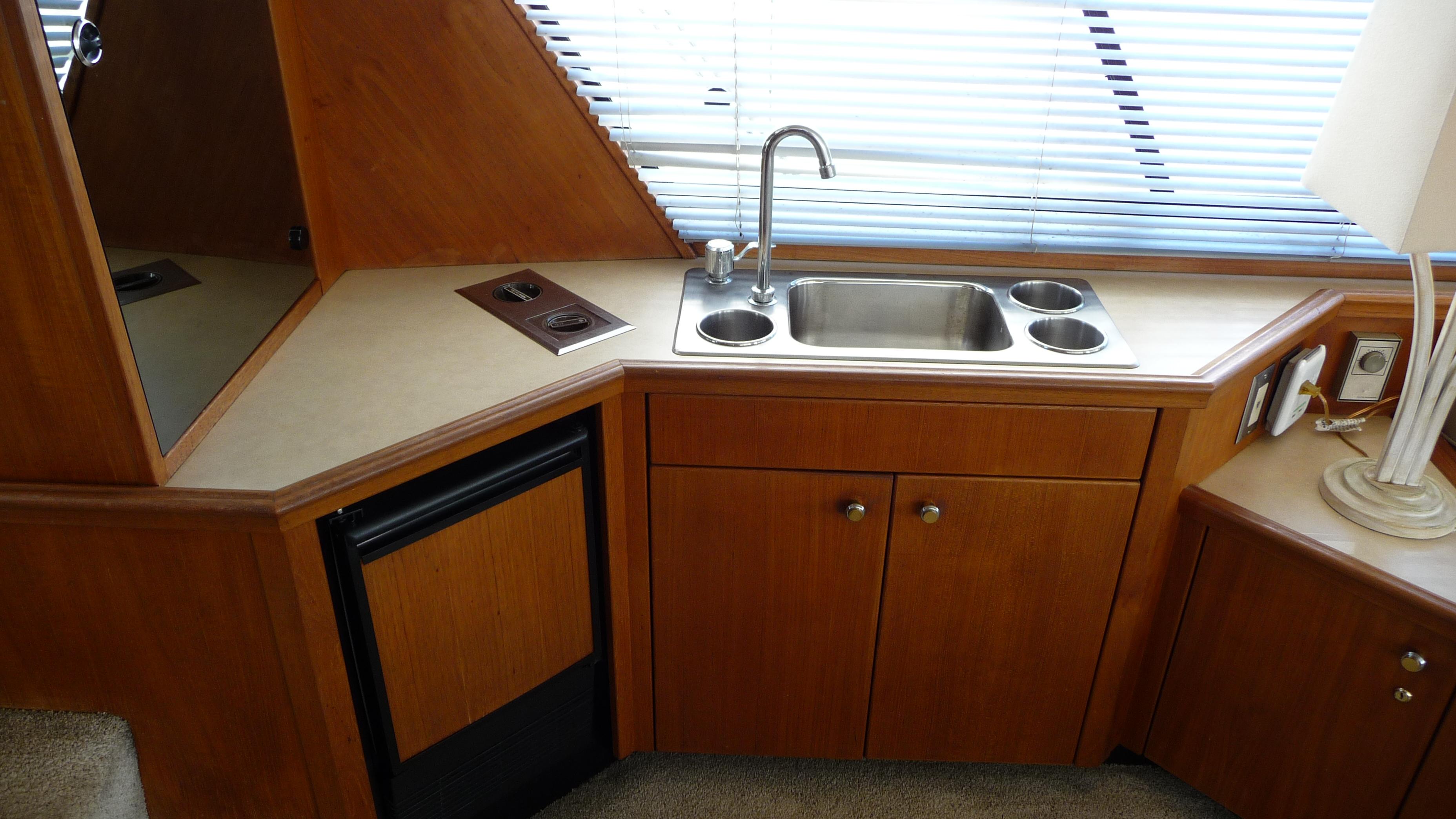 Compact kitchen area in a 1995 Bayliner 4788 Pilot House Motoryacht with sink and mini fridge.