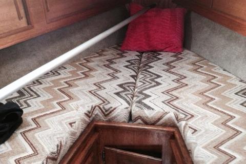 Interior cabin of a 1980 Sloop 27.7 Bristol with patterned bedding and wooden storage.
