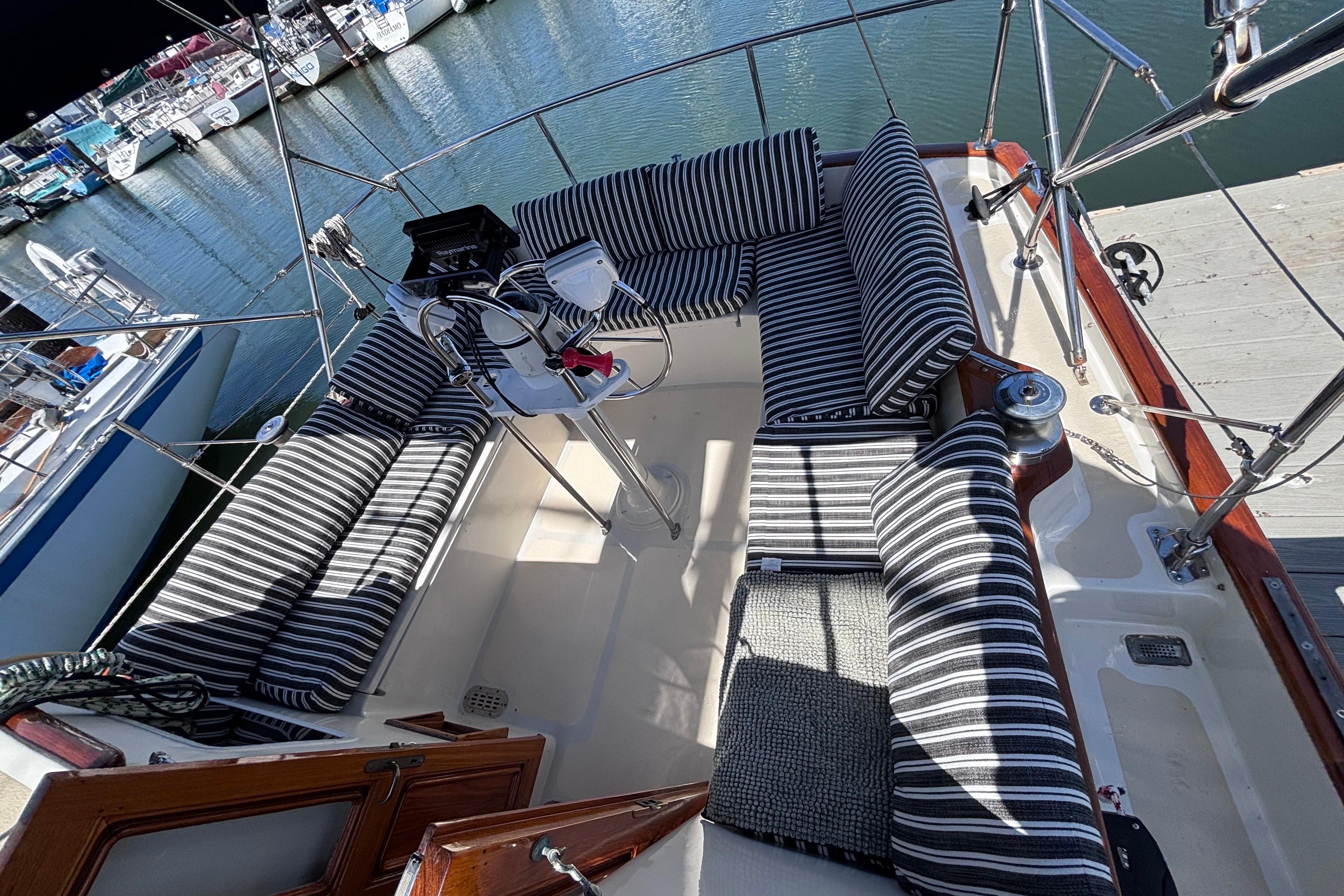 Cockpit of a 1978 Swift 33 sailboat with striped cushions, docked at a marina.