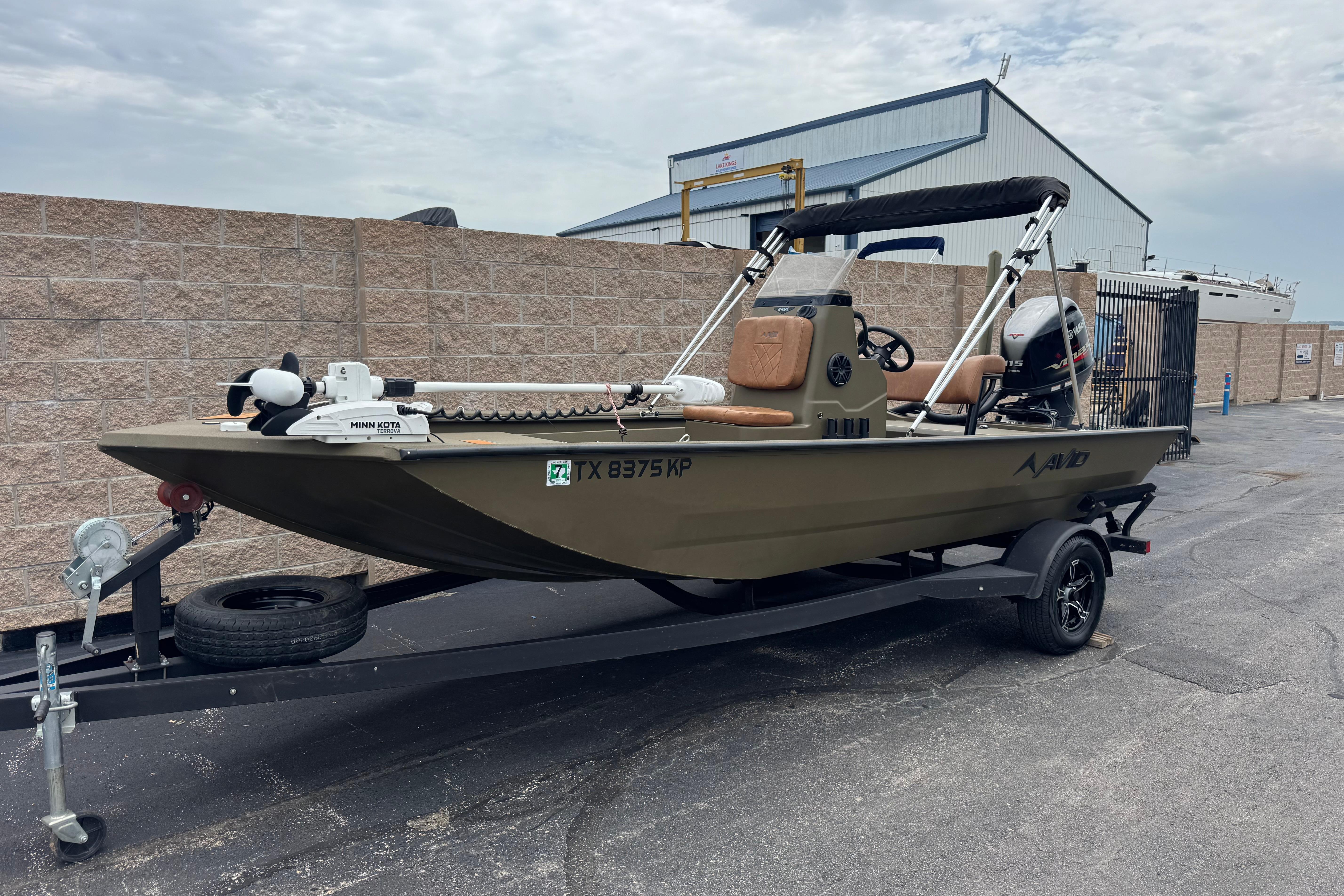 2023 Avid 18 Rogue CC boat on trailer, parked outdoors near industrial building.