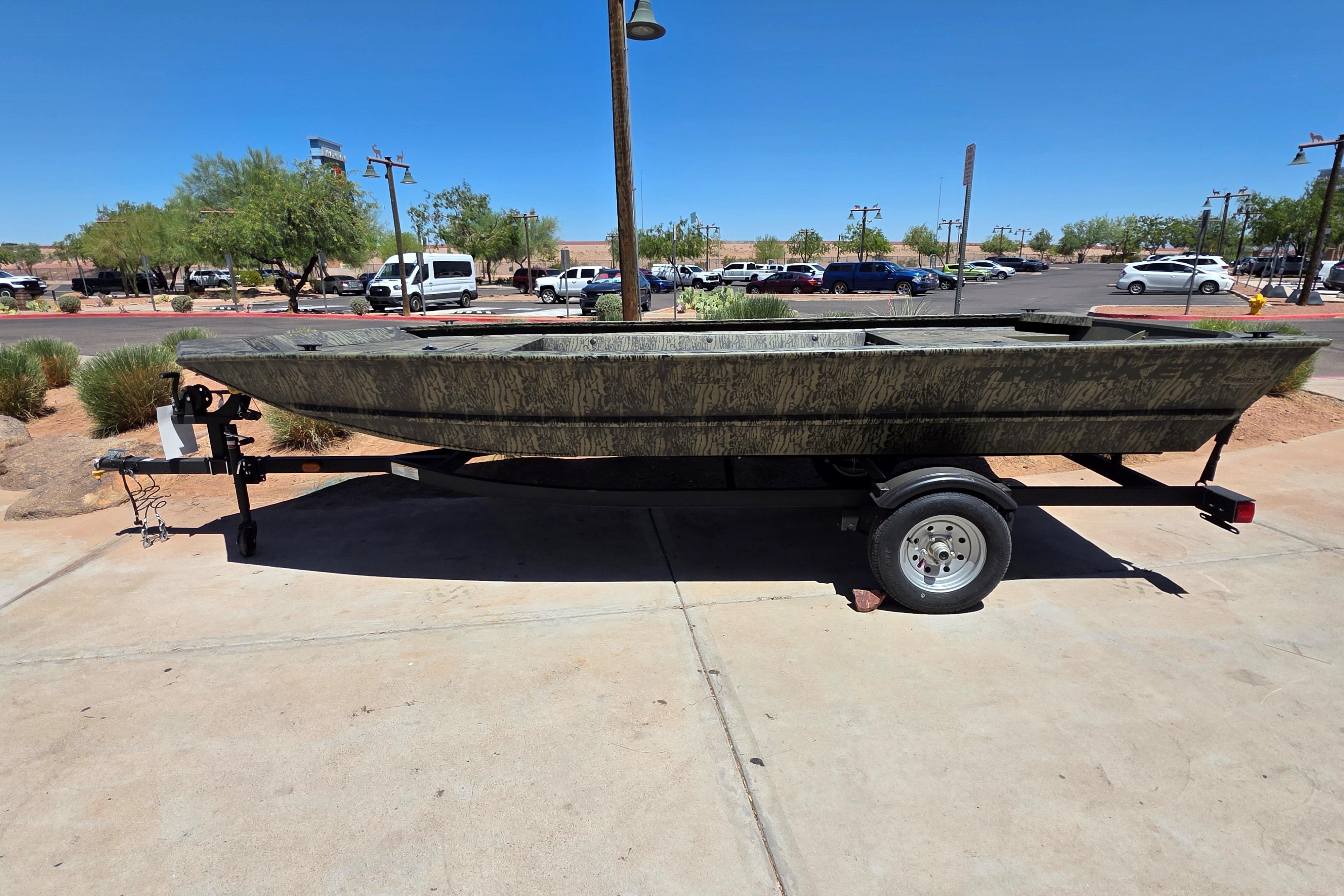 2026 Tracker Grizzly 1648 Utility boat on trailer in sunny parking lot.