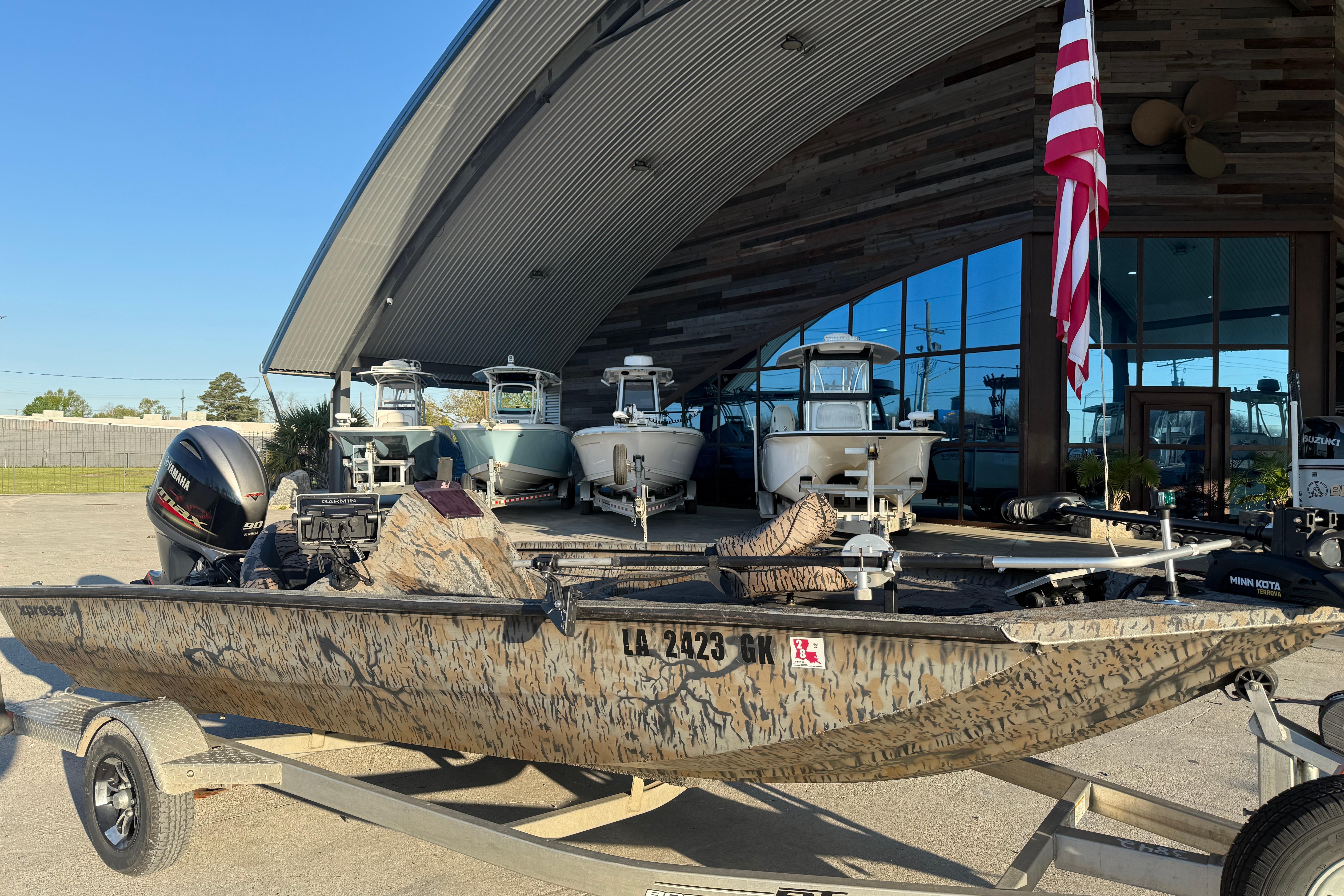 2019 Xpress XP7 boat with camouflage design on a trailer outside a showroom.