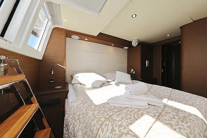 Luxurious bedroom interior of 2018 Lagoon 620 Esense yacht with elegant bedding and natural light.