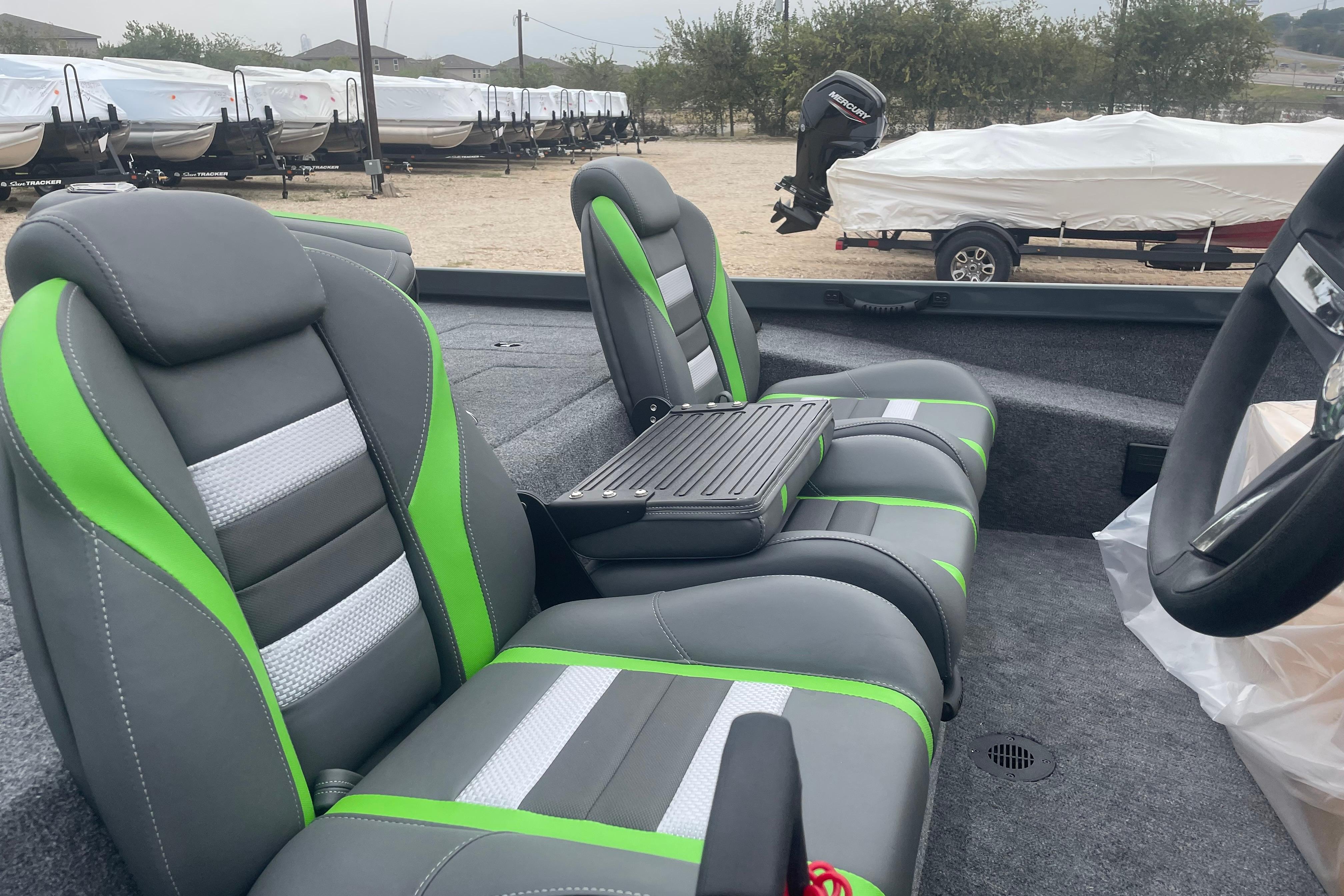 2026 Ranger RT188 boat interior with gray and green seats, parked with covered boats nearby.