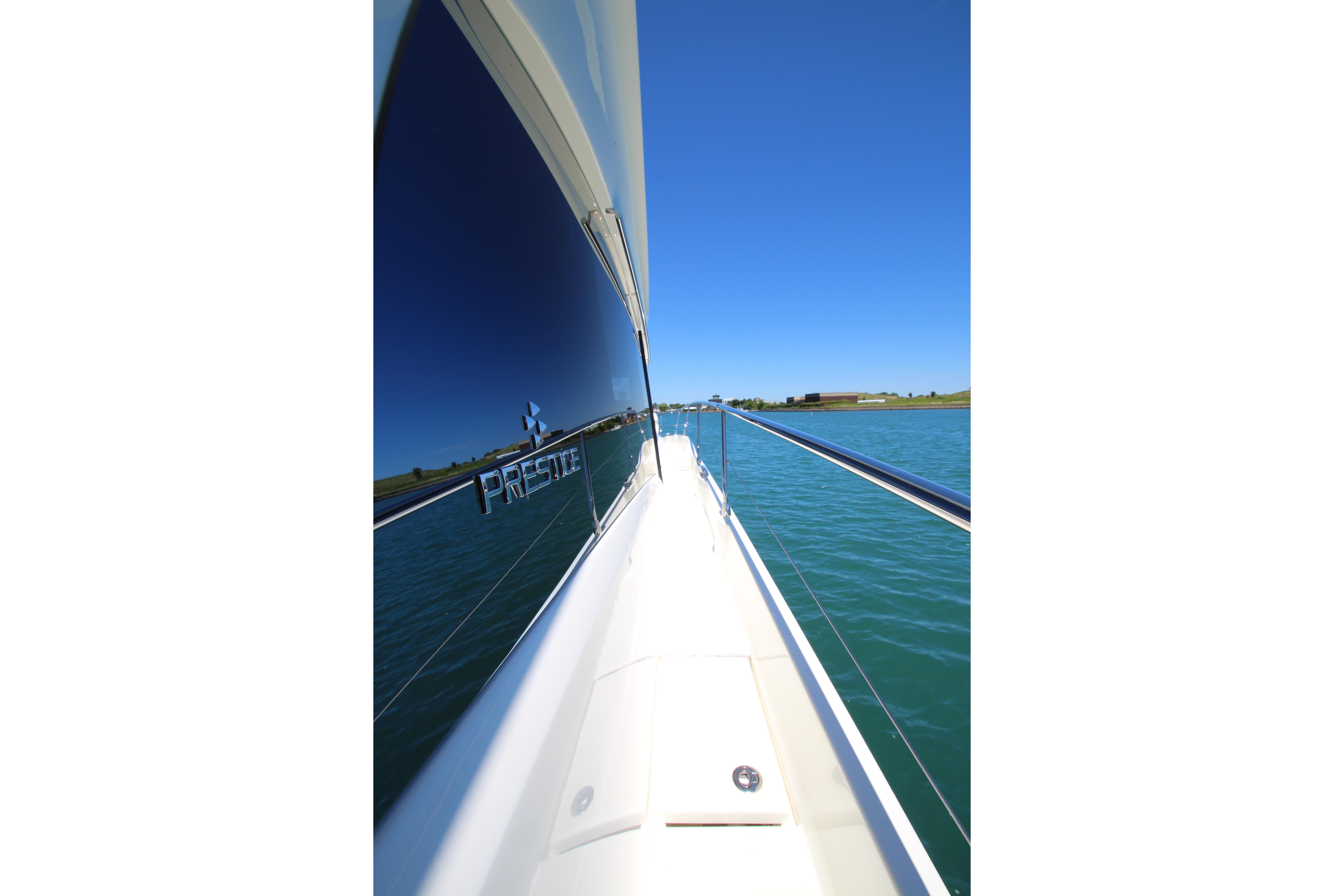 Side view of a 2022 Prestige 520 yacht cruising on clear blue water.