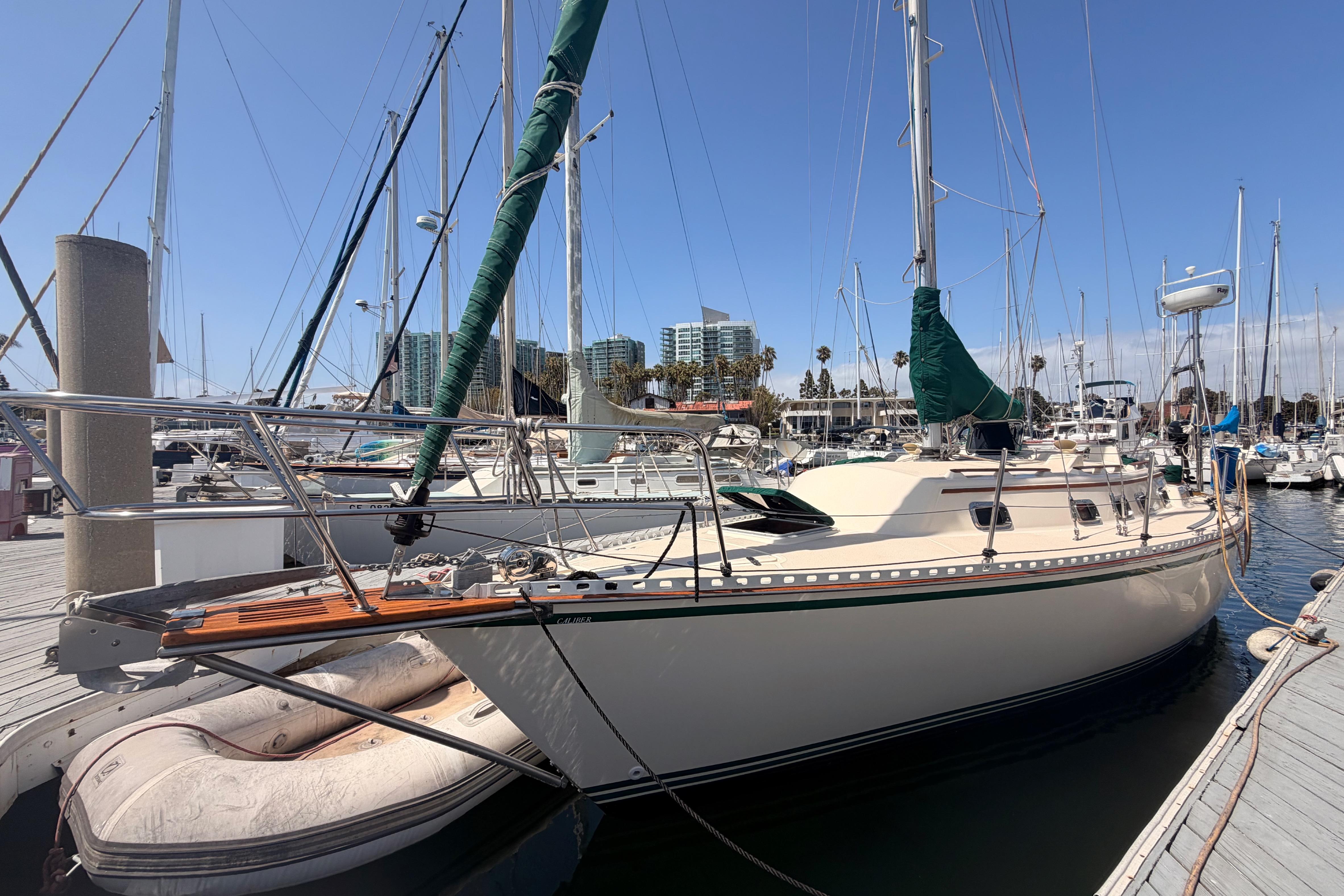 Sailboat docked at marina, 1991 Caliber 33 model, clear sky, urban backdrop.