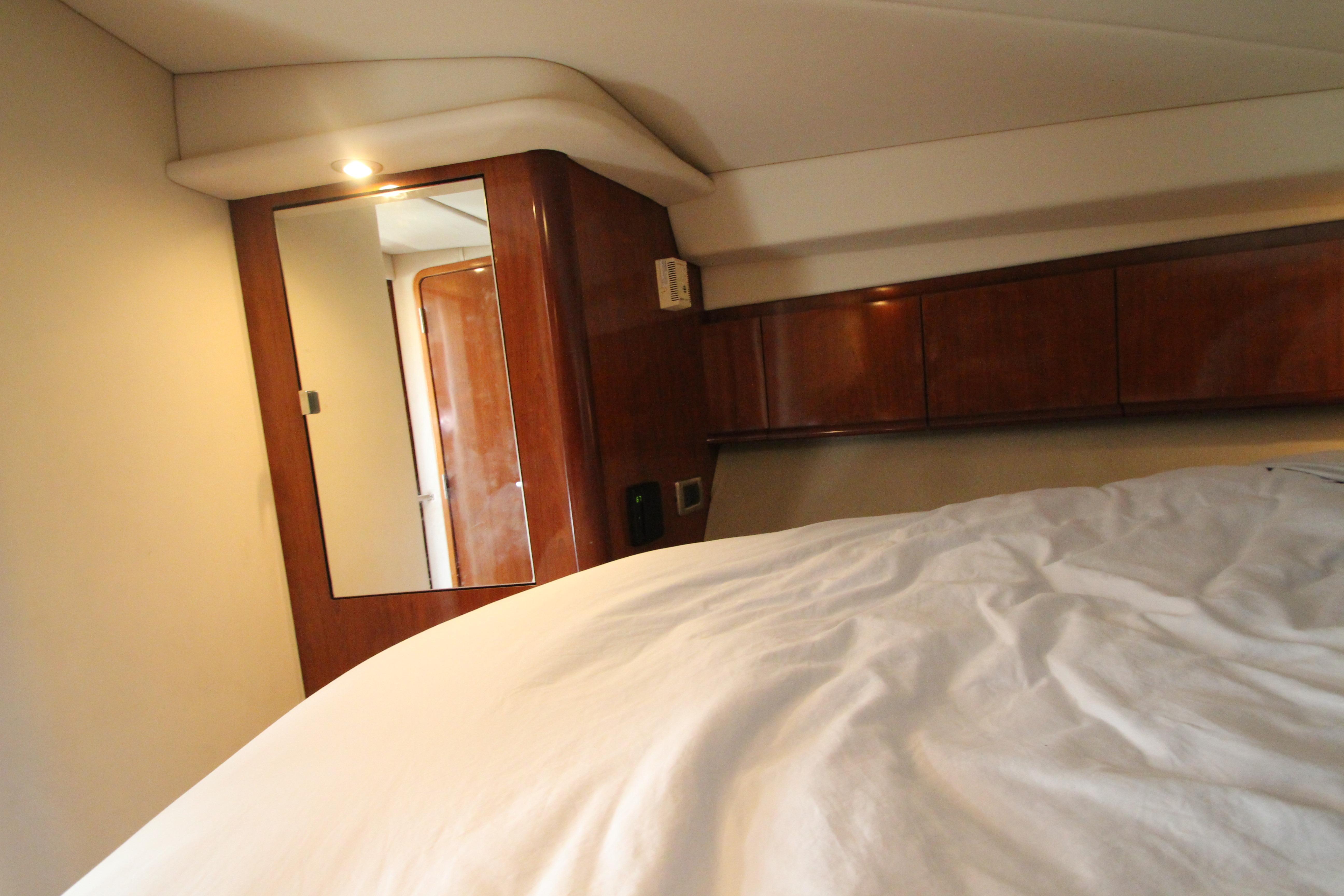 Interior cabin of 2004 Sea Ray 40 Sundancer yacht with wooden cabinetry and bed.