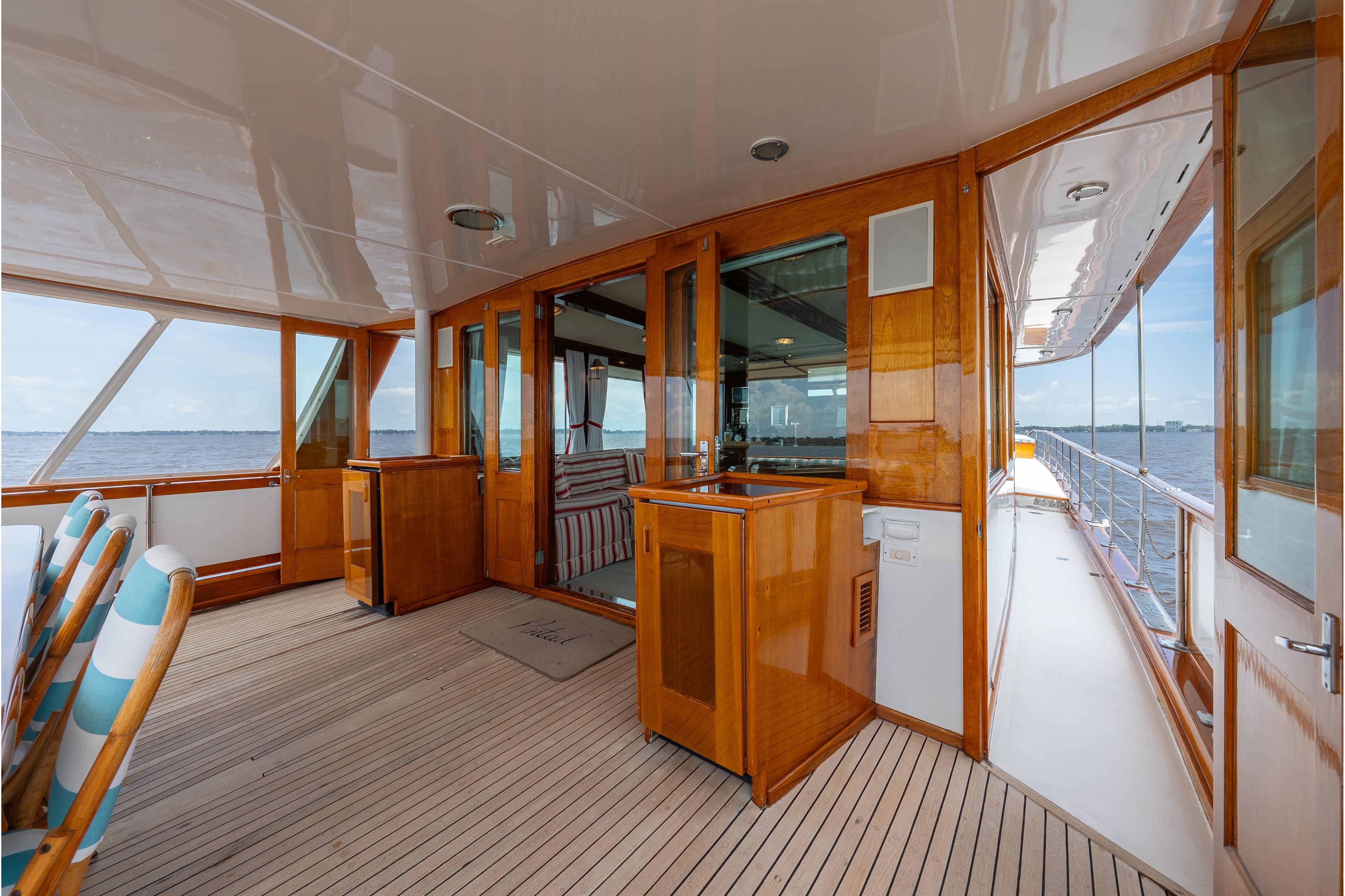 Luxurious 1963 Trumpy Classic yacht deck with polished wood and ocean view.